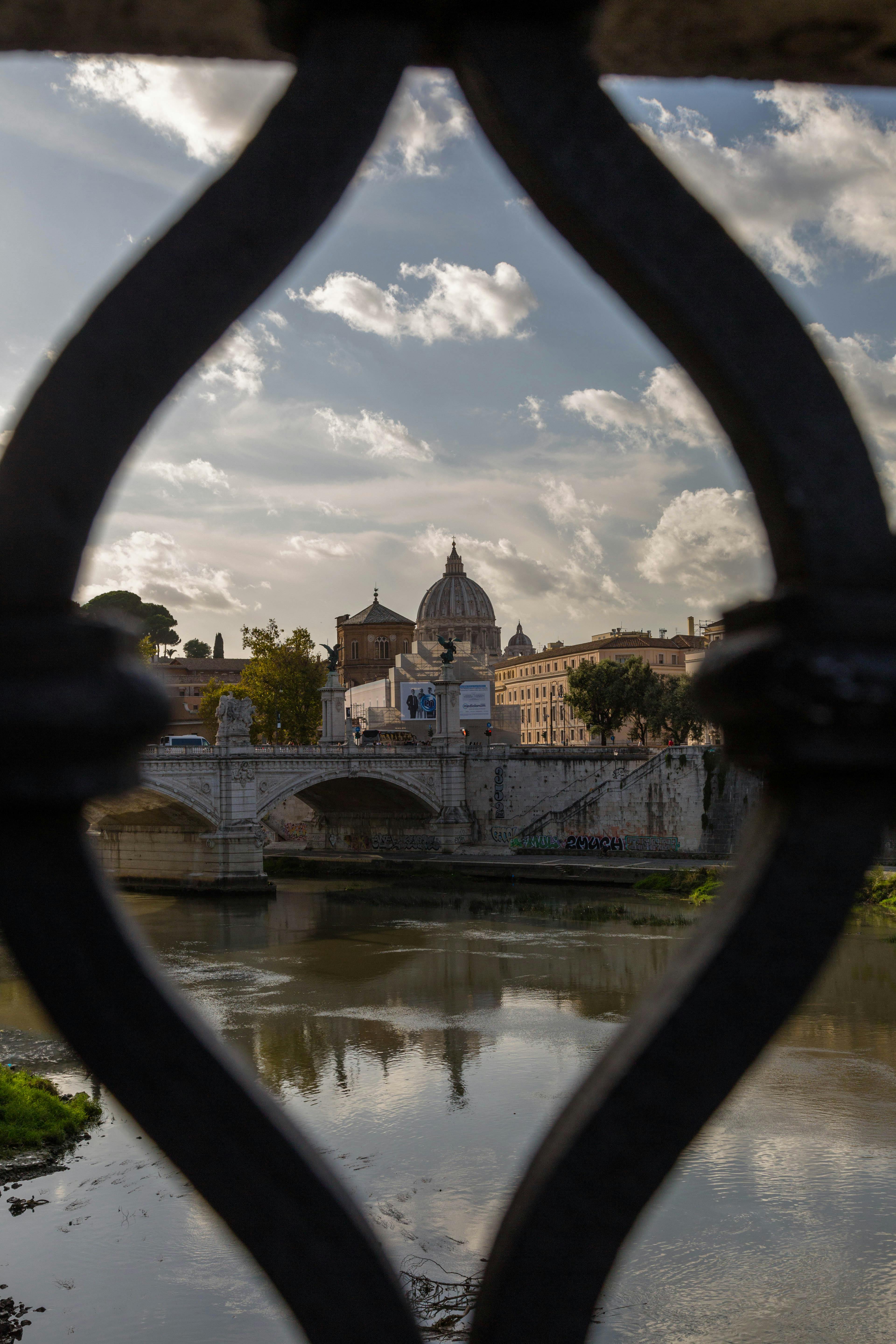 Miễn phí Cảnh tượng ngoạn mục của Vương cung thánh đường Thánh Phêrô nhìn qua hàng rào sắt chạm khắc tinh xảo, ghi lại trọn vẹn vẻ đẹp đặc trưng của đường chân trời La Mã. Ảnh lưu trữ