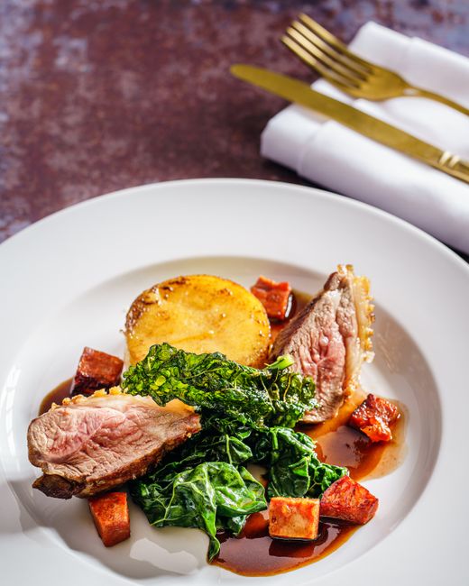 Savor a gourmet dish of roast lamb, crispy kale, and polenta, perfect for fine dining.