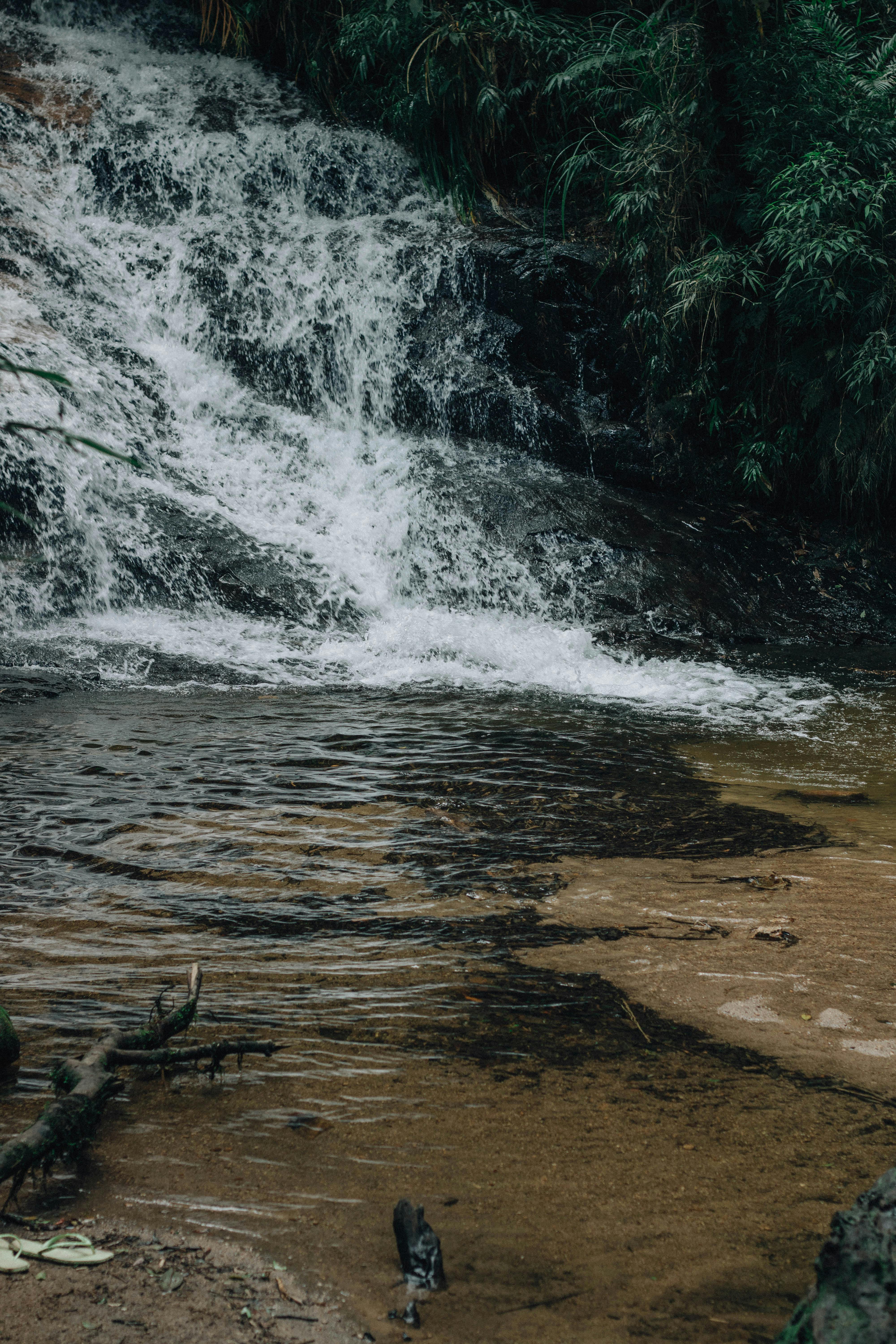 gratis Een schilderachtige waterval die door een dicht bos naar beneden stort en een rustige, natuurlijke ontsnapping biedt. Stockfoto