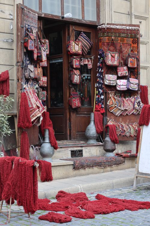 Free Vibrant textile shop entrance displaying colorful rugs and handmade bags in a charming setting. Stock Photo
