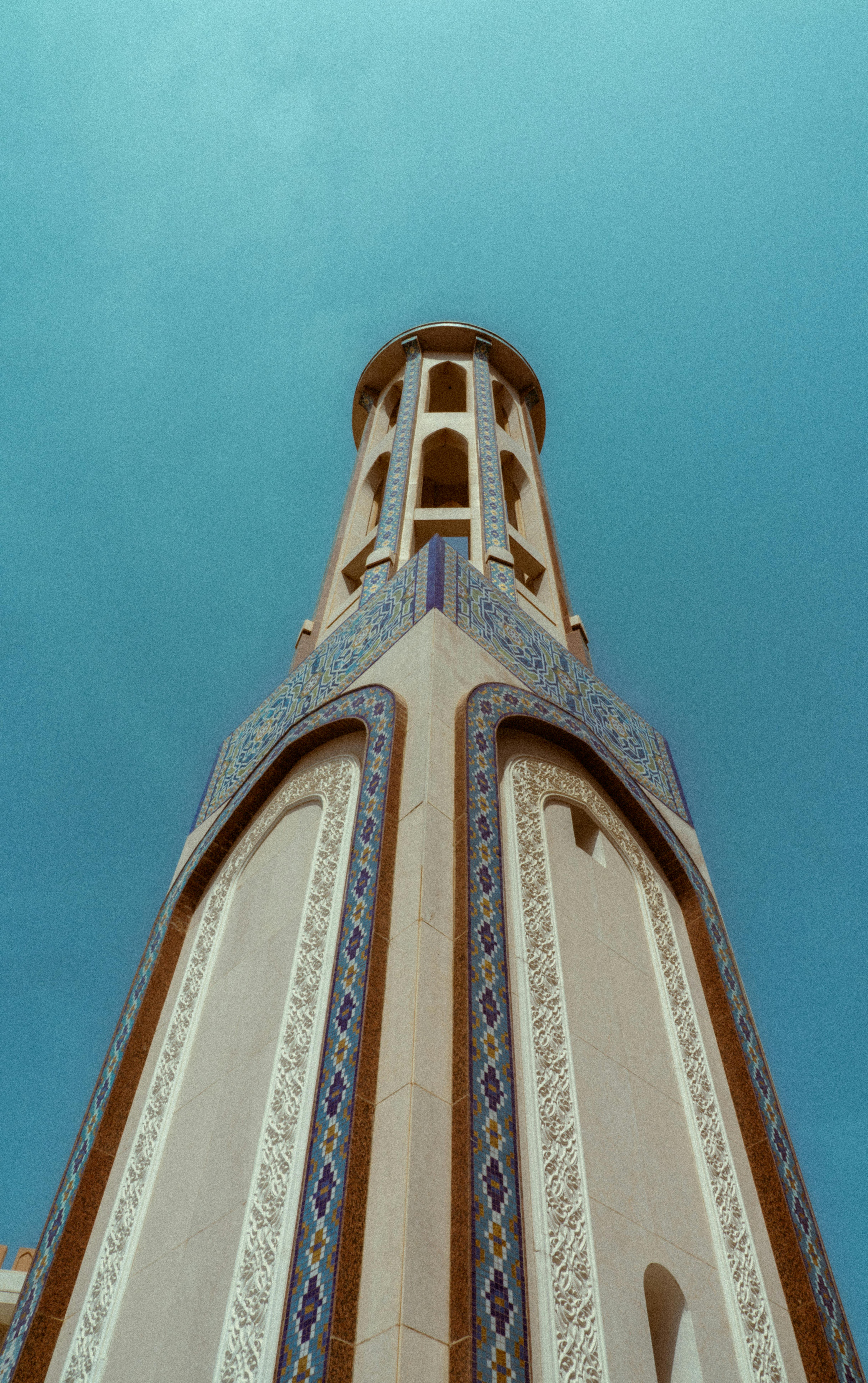 bezplatná Úchvatný pohled na zdobený minaret proti jasné modré obloze v Maskatu v Ománu. Základová fotografie