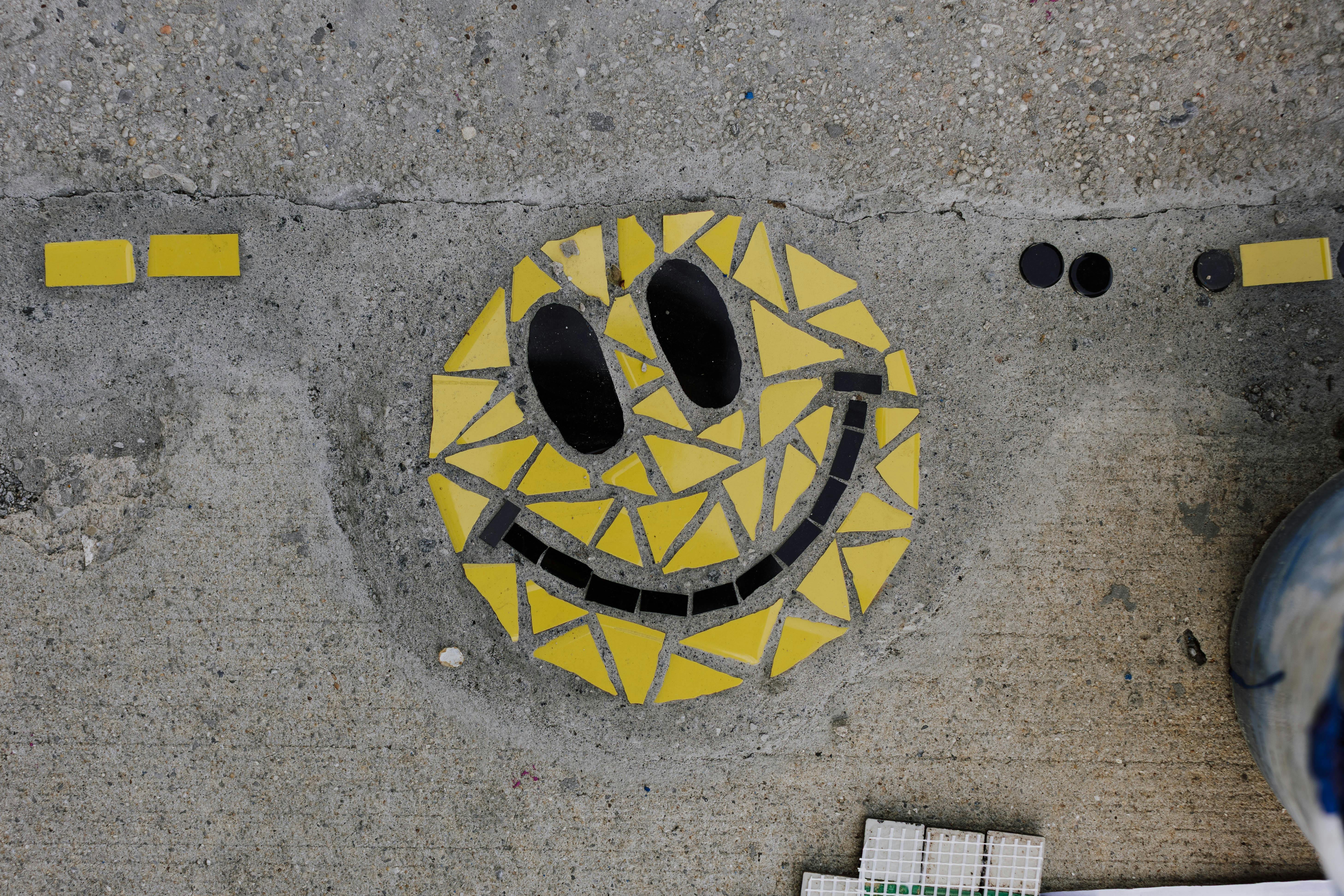 ingyenes Élénk sárga mozaik mosolygós arccal díszített beton járda. Stockfotó