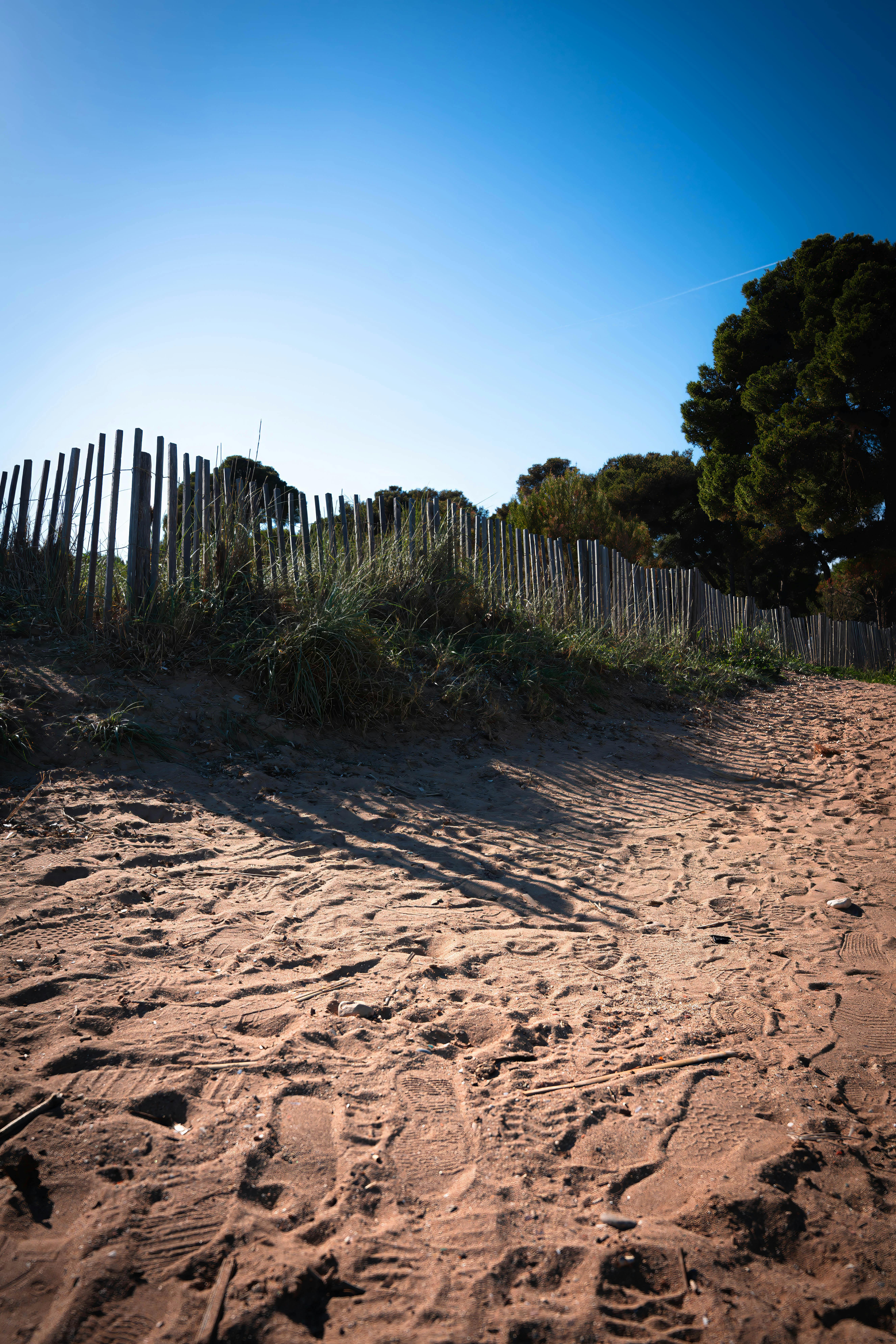 Free A scenic sandy path with a wooden barrier in Hyères, France under a clear blue sky. Stock Photo