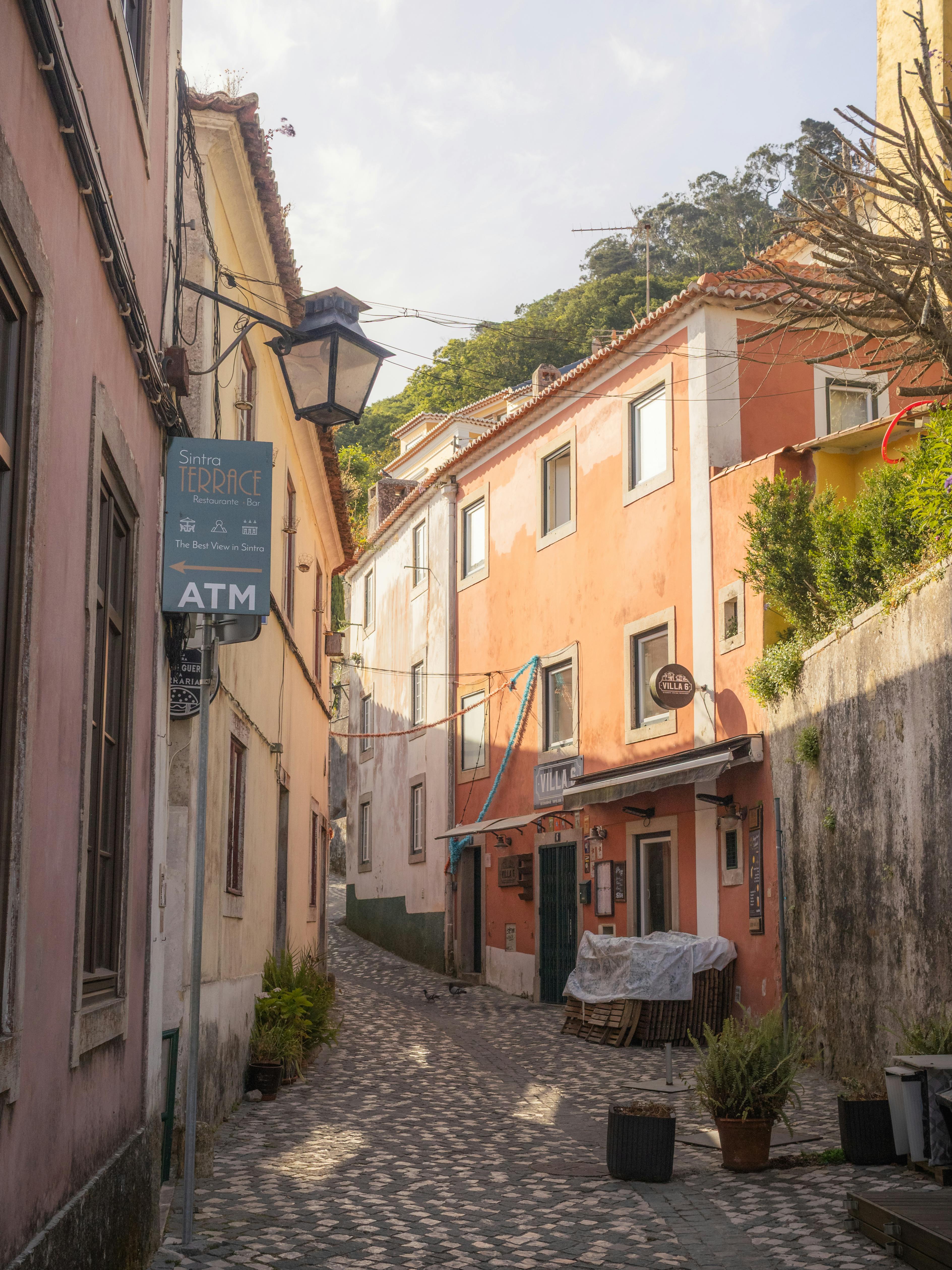 Bezpłatne Malownicza wąska uliczka w Sintrze, w Portugalii, z kolorowymi budynkami i brukowaną ścieżką. Zdjęcie z galerii