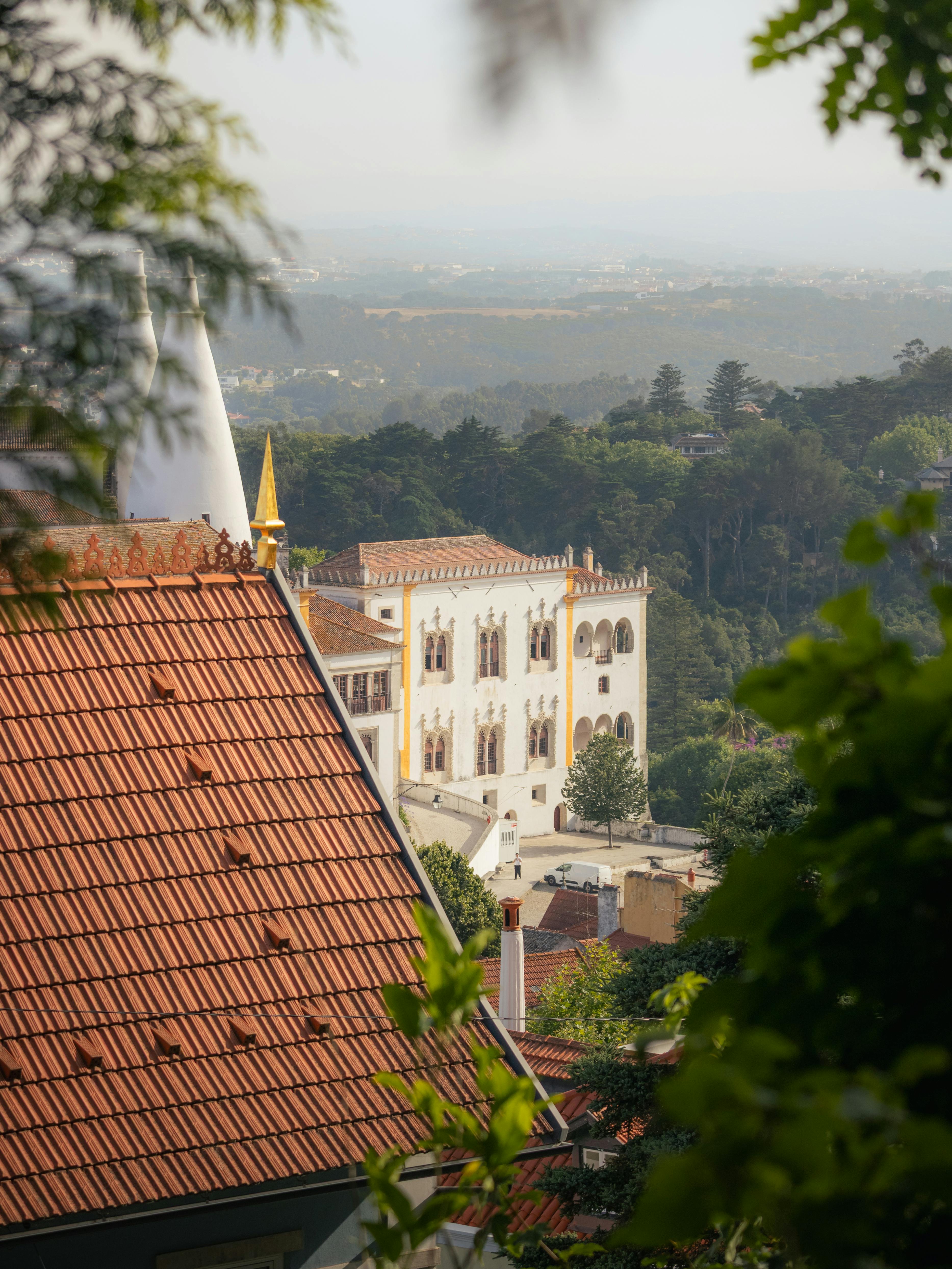 bezplatná Podmanivý pohled na palác Sintra v Portugalsku, obklopený zelenými lesy, představuje architektonickou krásu a přírodní harmonii. Základová fotografie