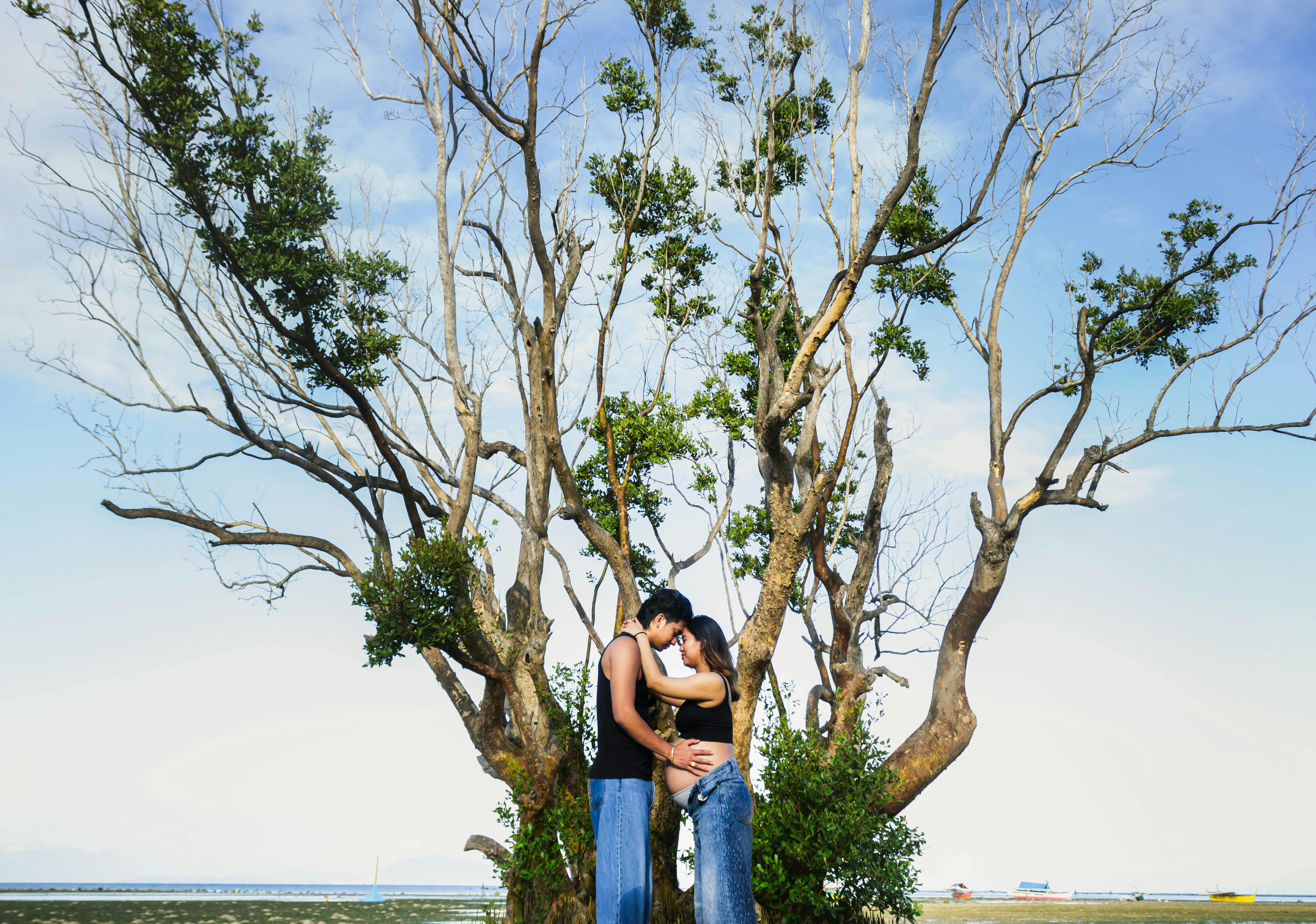 Zadarmo Romantický pár objímajúci sa pod veľkým stromom v pokojnom vonkajšom prostredí. Fotka z fotobanky
