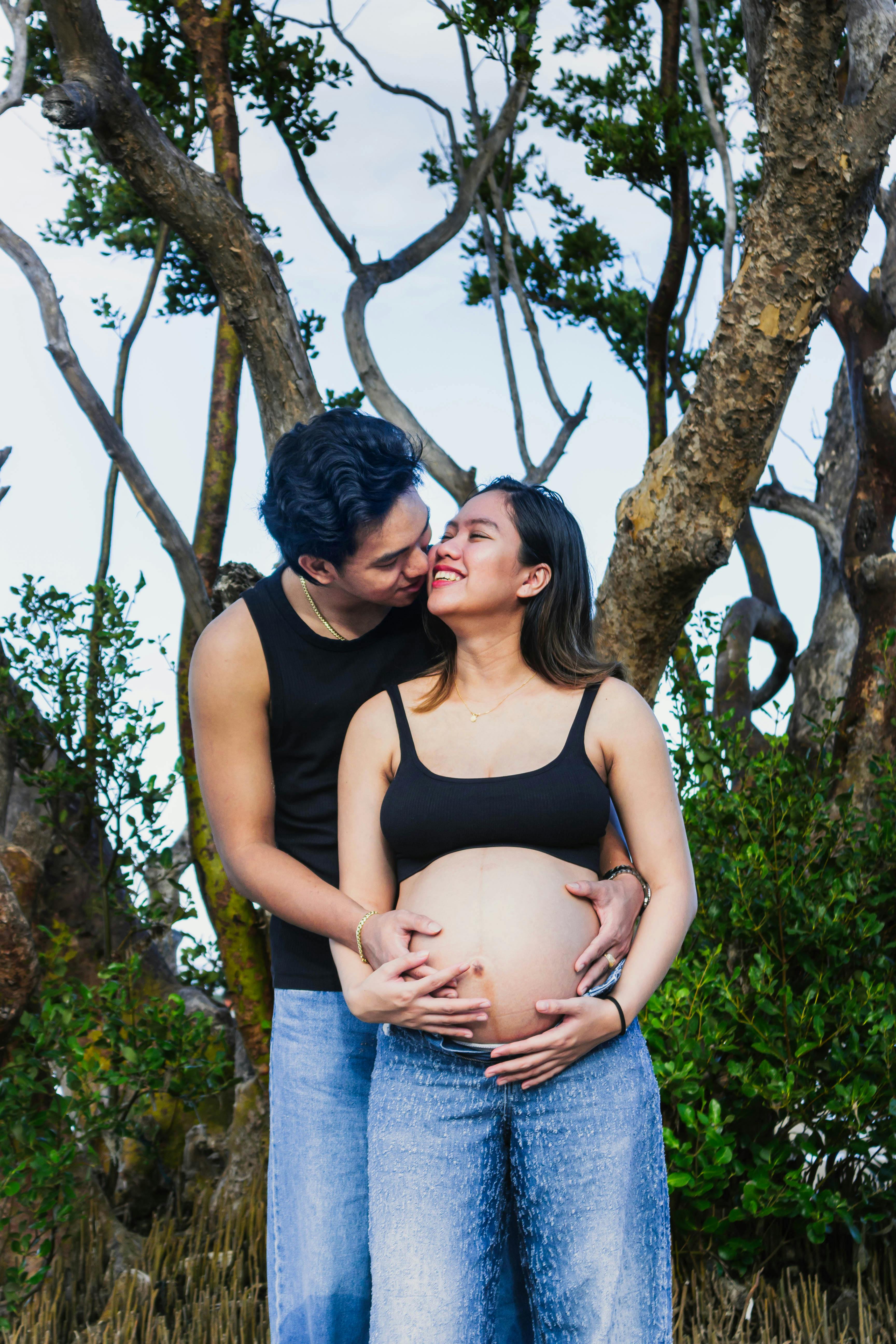 免费 一对幸福的夫妇在户外享受着甜蜜的时光，周围环绕着大自然，孕期也十分惬意。 素材图片