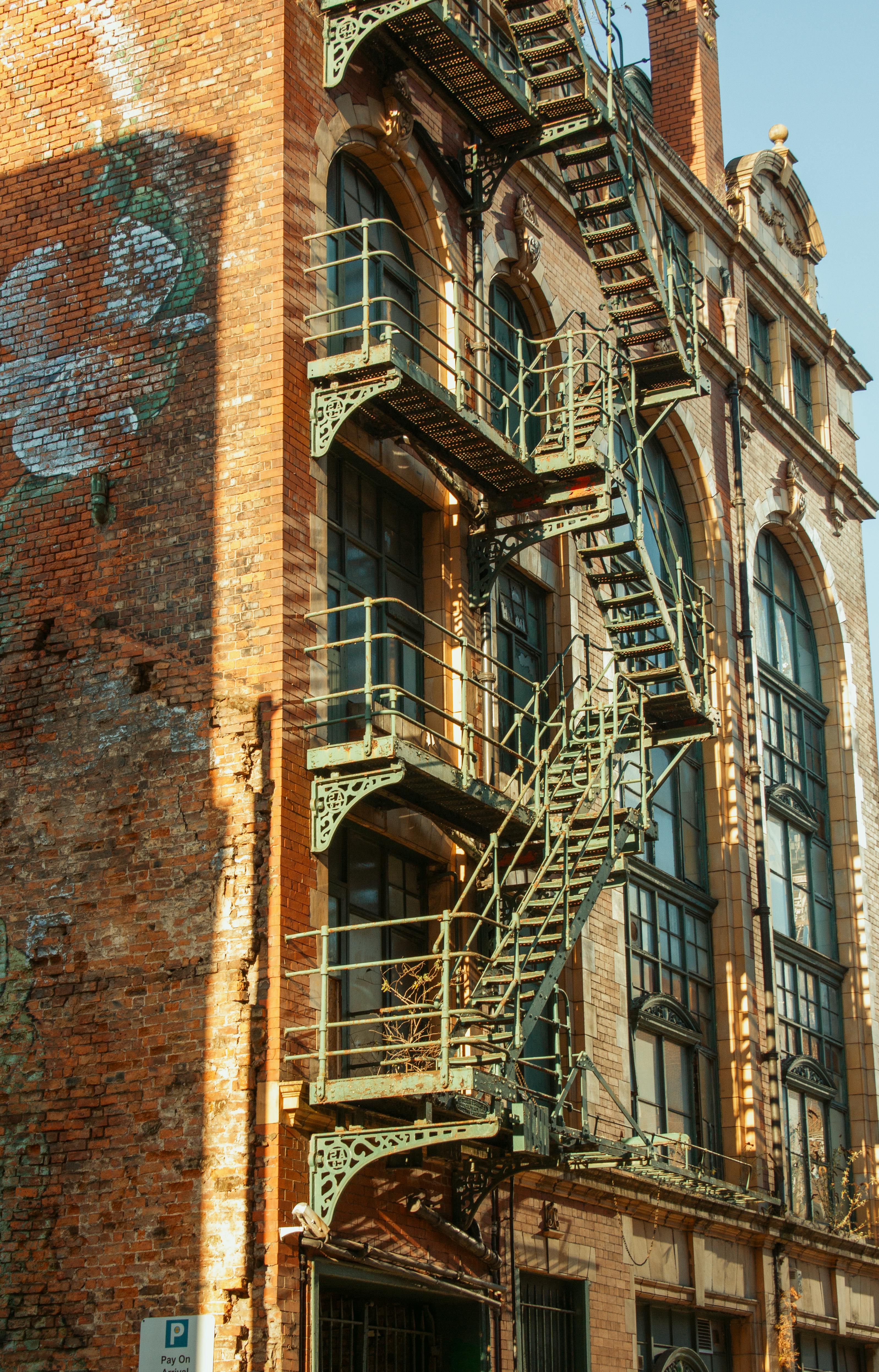 무료 맨체스터에 있는 유서 깊은 산업 건물로, 벽돌 외관을 배경으로 독특한 금속 계단이 눈에 띕니다. 스톡 사진