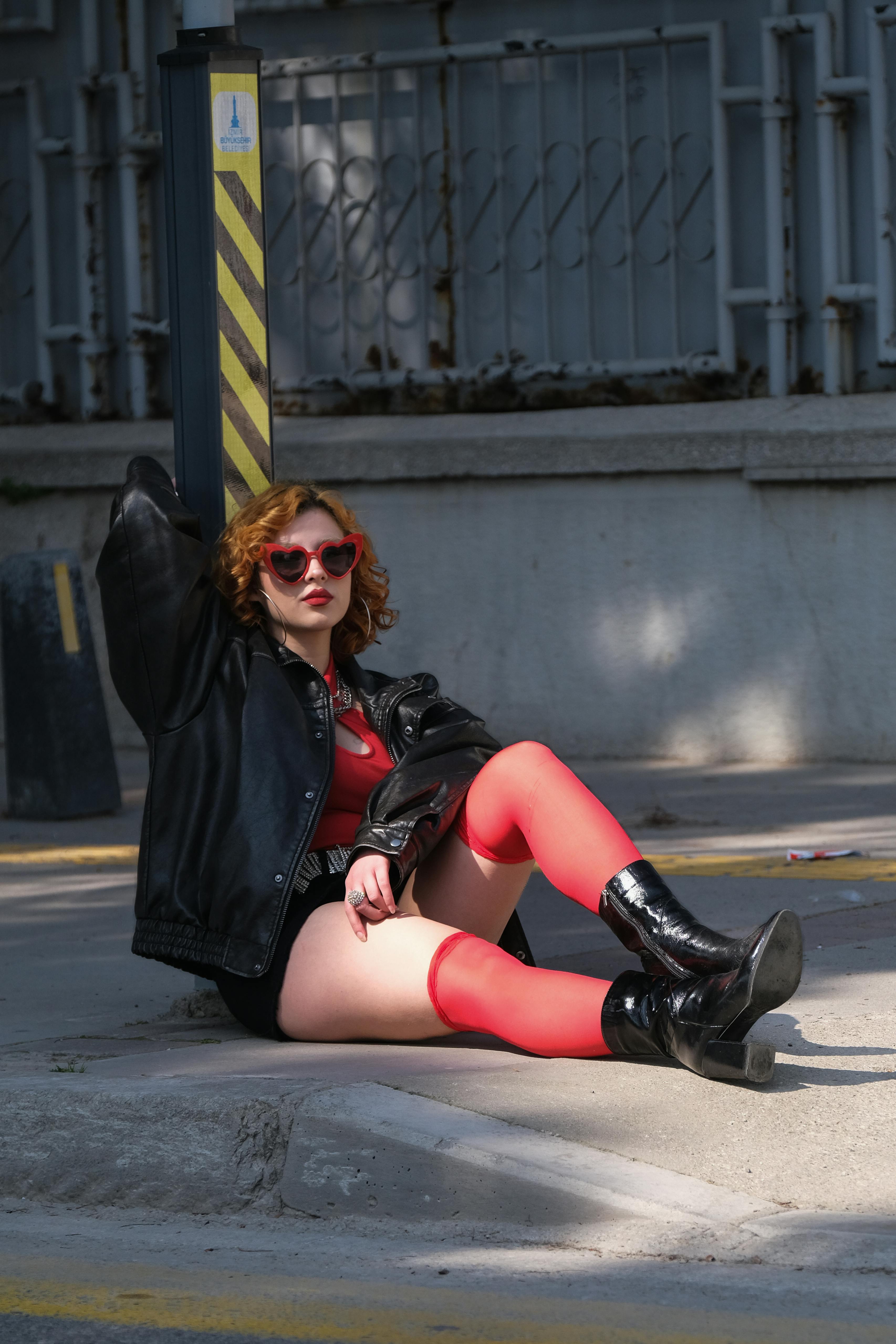 Zadarmo Trendy žena v červenej a čiernej farbe sebavedomo sedí vonku v štýlovom mestskom prostredí. Fotka z fotobanky