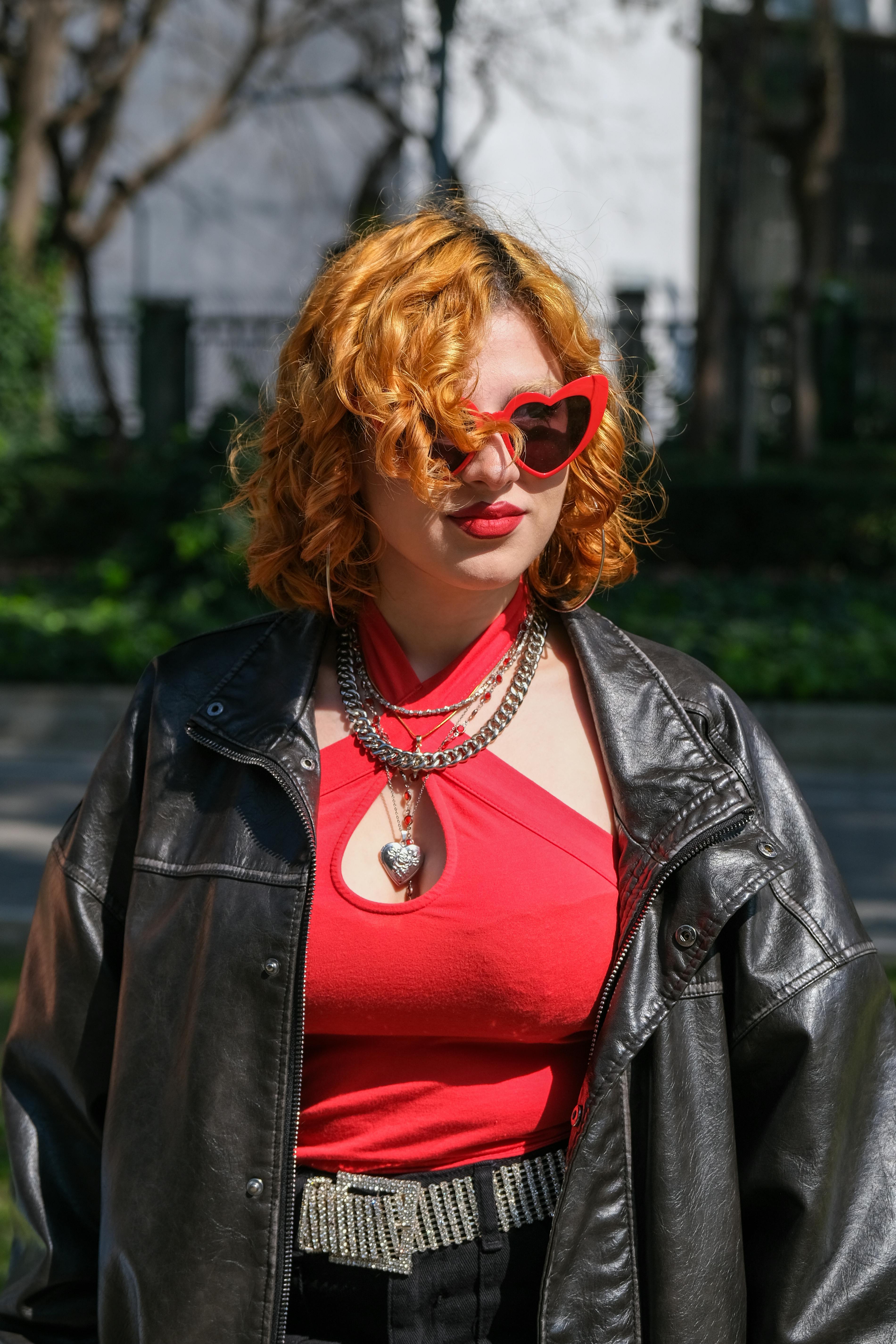 Zadarmo Módna žena s kučeravými vlasmi v slnečných okuliaroch štýlovo pózuje v mestskom parku. Fotka z fotobanky