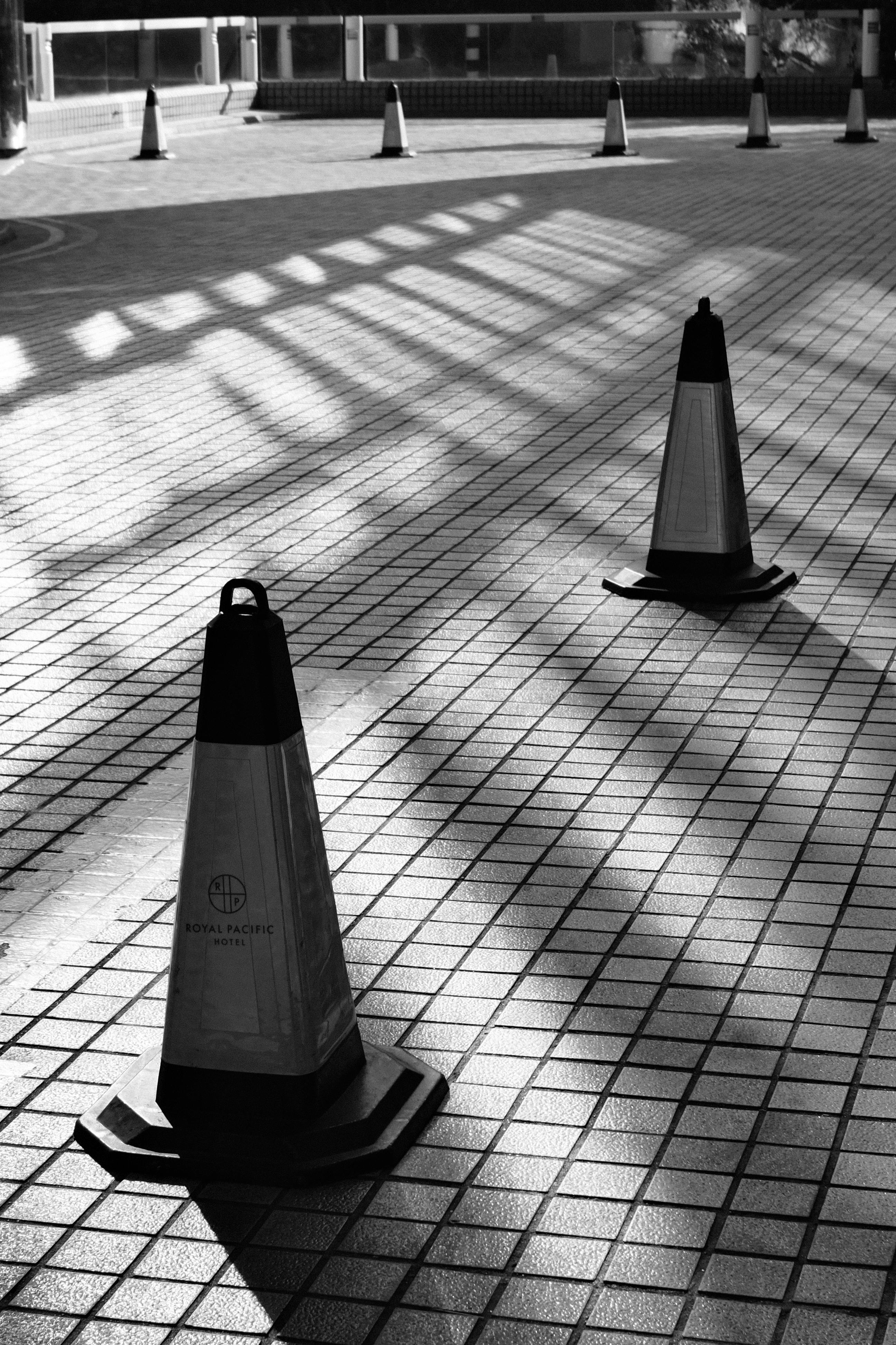 Безкоштовне Художня чорно-біла фотографія дорожніх конусів, що відкидають тіні на плитковий тротуар у Гонконзі. стокове фото