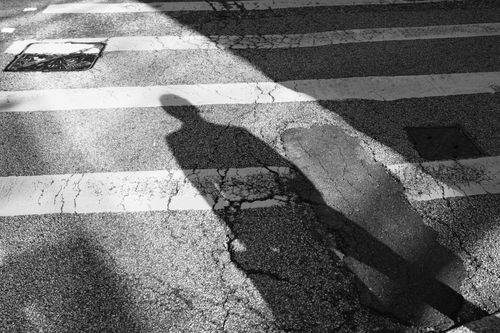 Free Silhouette of a person on a zebra crossing casting a shadow, in urban Hong Kong. Stock Photo