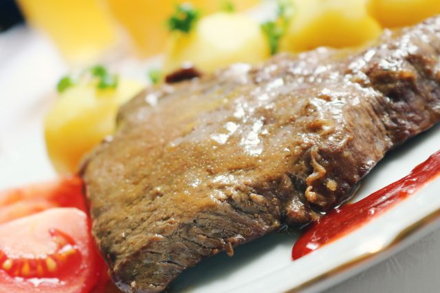 Mouth-watering steak served with potatoes and fresh tomato slices. Perfect for lunch or dinner.
