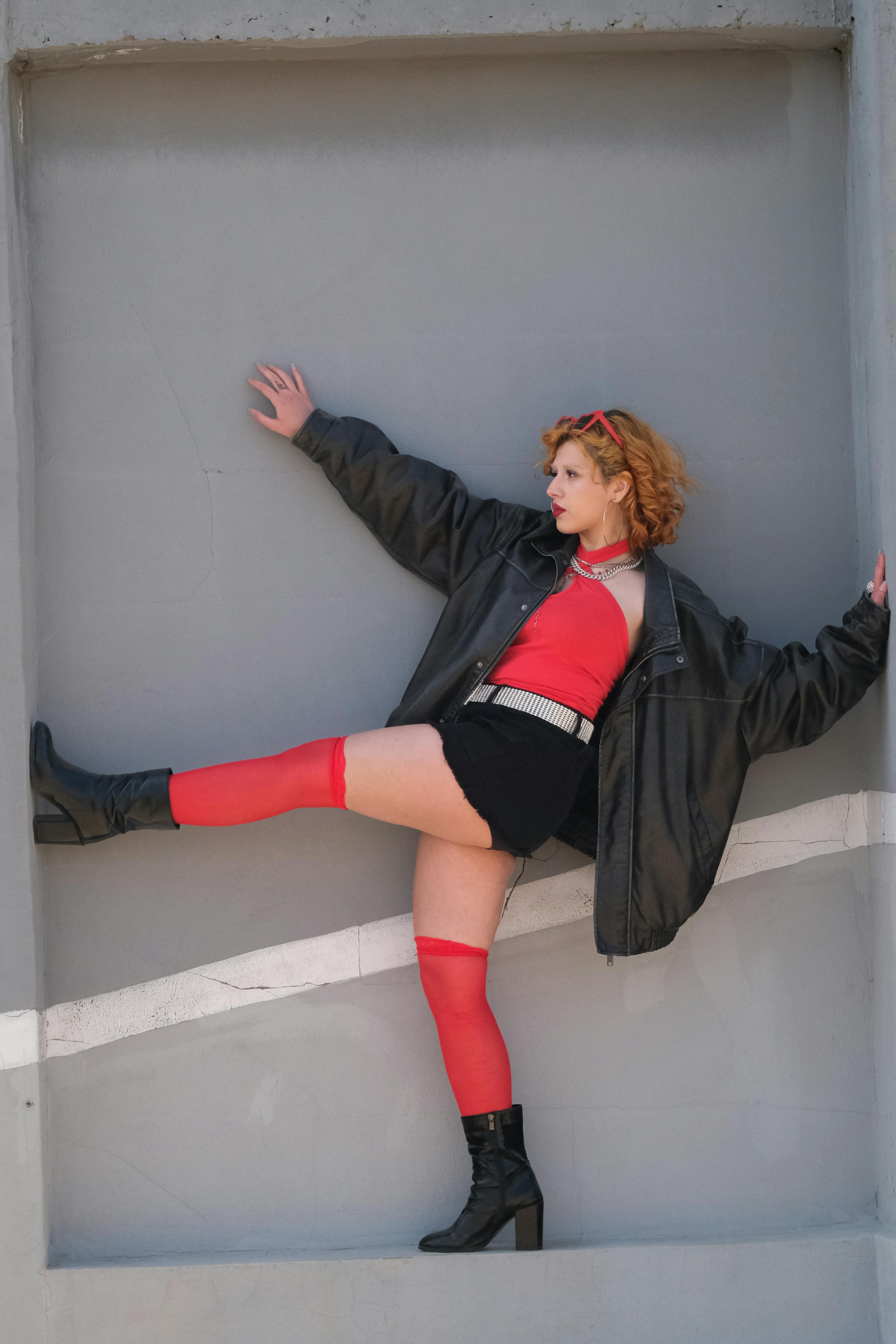 Безкоштовне Модна жінка в червоному та чорному позує в міському середовищі. Сміливий, сучасний стиль. стокове фото