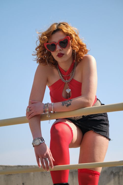 Free Fashionable woman posing in red attire and heart sunglasses outdoors. Stock Photo