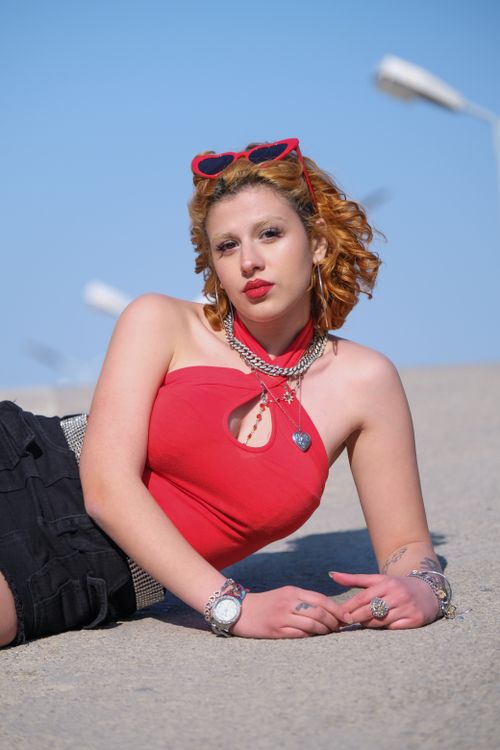 Free Stylish woman in chic red top and accessories posing outdoors under the sun. Stock Photo