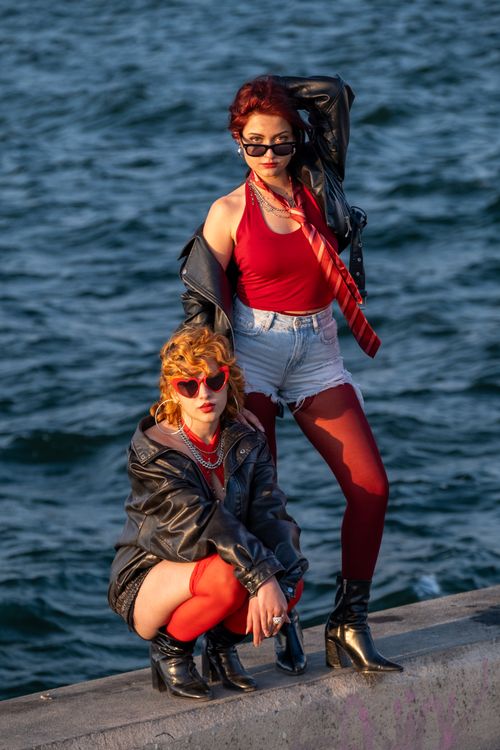 Free Two stylish women in edgy fashion posed by the waterfront in evening light. Stock Photo