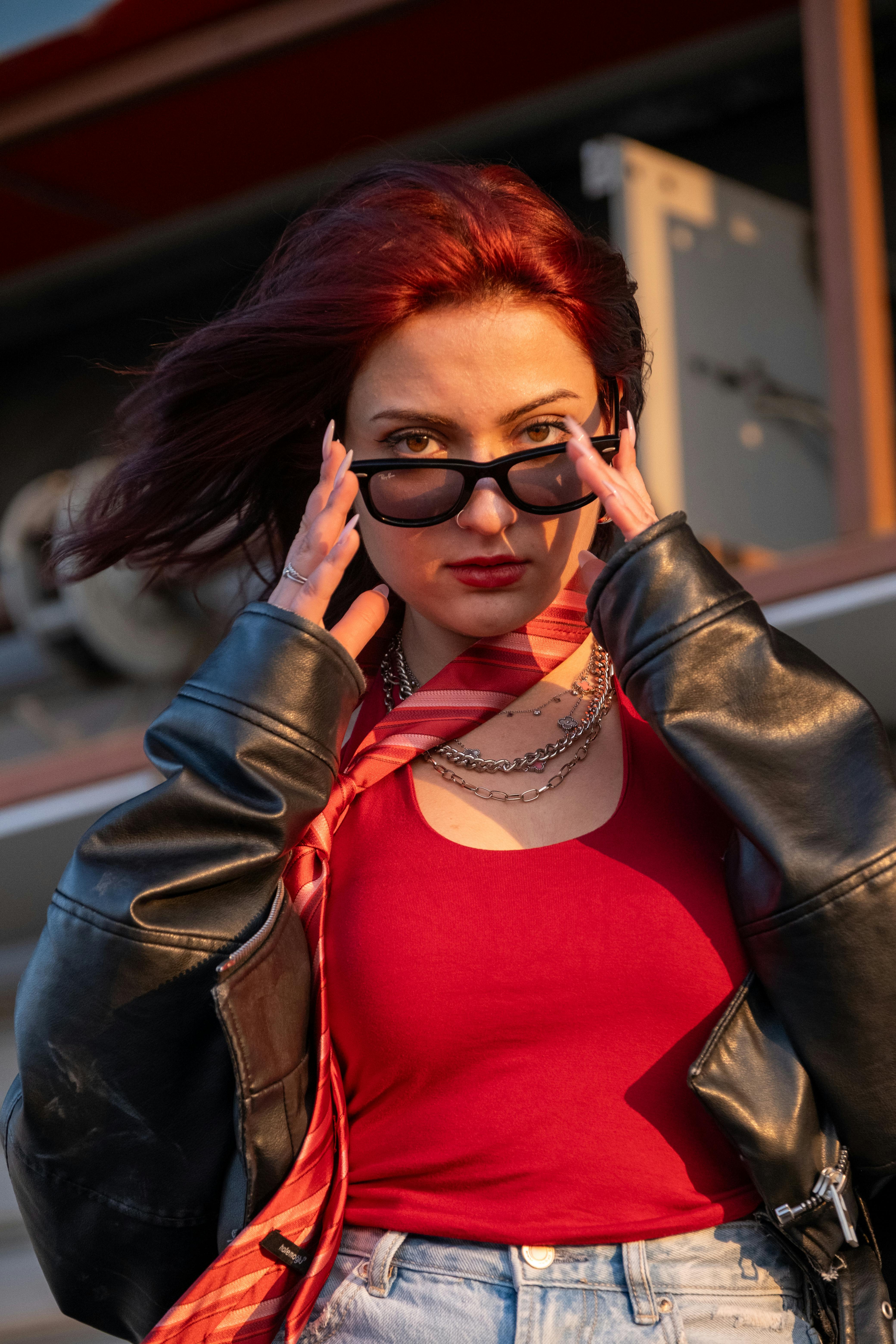 ingyenes Magabiztos vörös hajú, napszemüveges nő a szabadban, bőrkabátban. Stockfotó