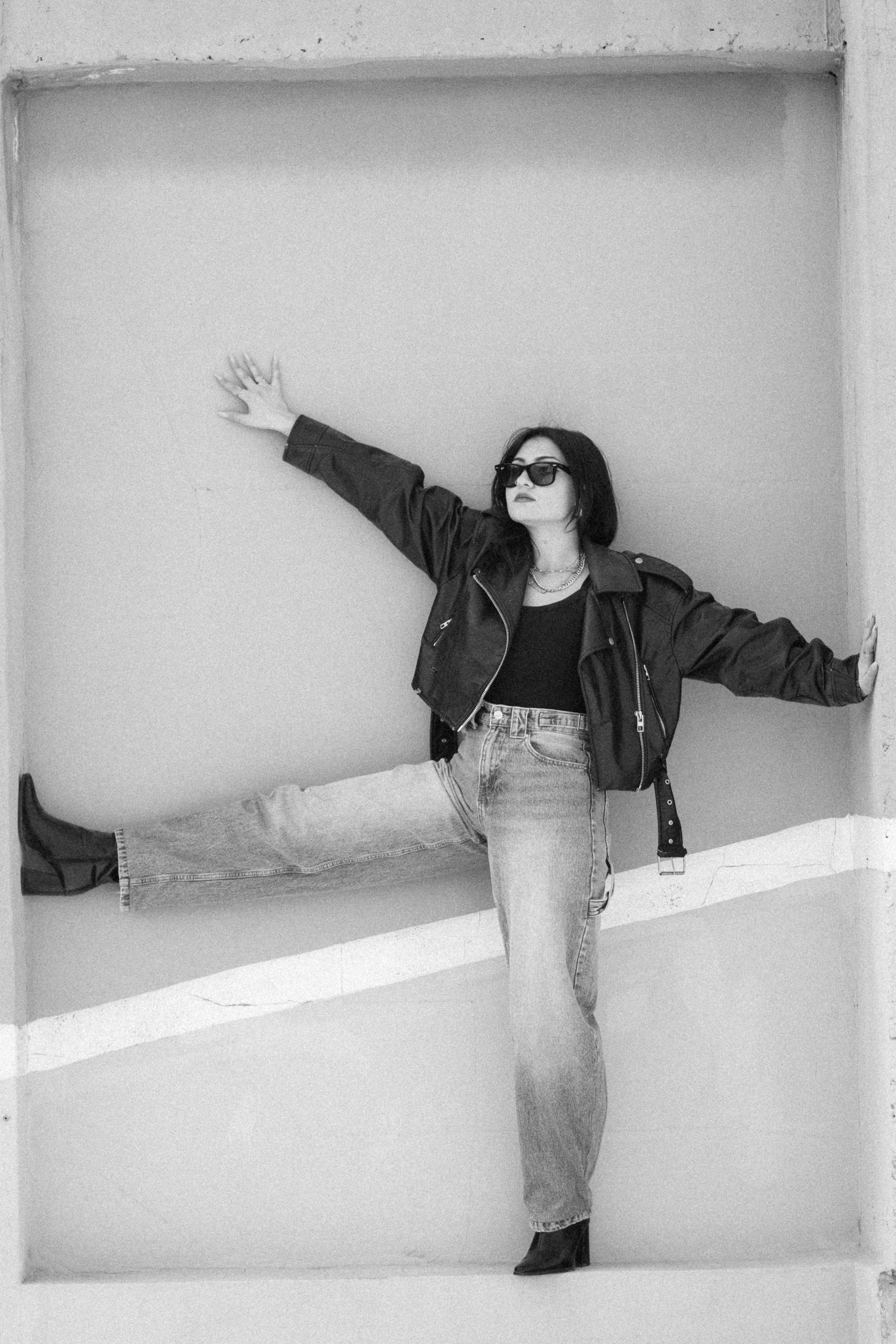 Miễn phí Ảnh đen trắng chụp một người phụ nữ trong tư thế vui tươi, mặc áo khoác da và đeo kính râm. Ảnh lưu trữ