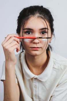 Portrait of a young woman holding a paintbrush with a serious expression indoors.