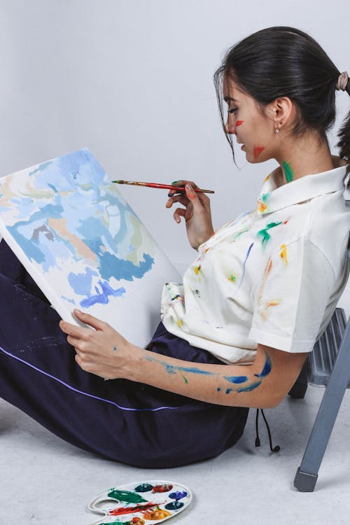 地面の絵画のキャンバスに座っている女性の側面写真