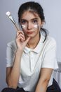 一名年轻女子在室内拿着一把涂着油漆的画笔摆姿势