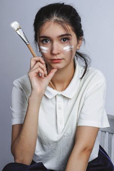 一名年轻女子在室内拿着一把涂着油漆的画笔摆姿势