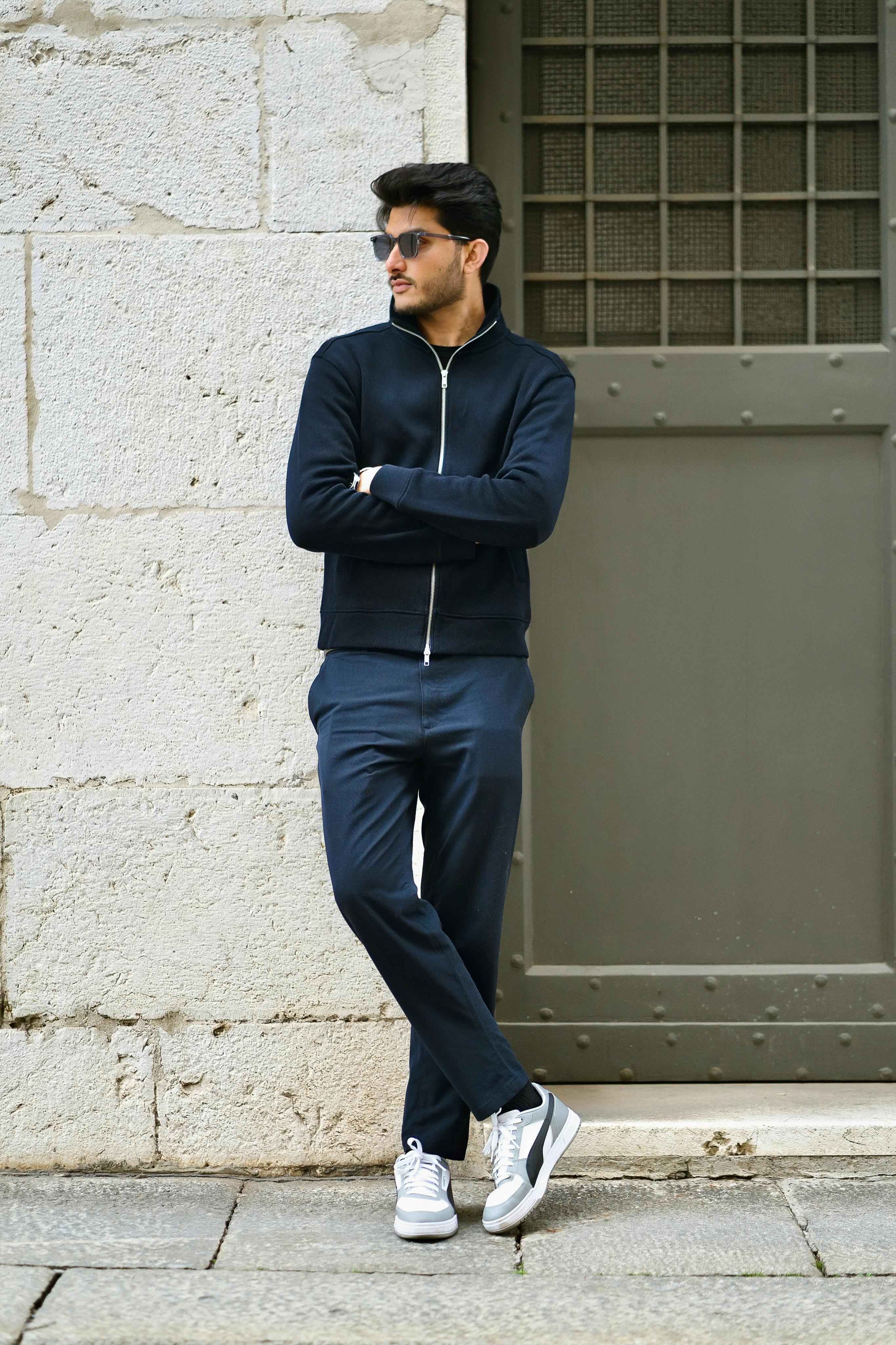 ingyenes Egy divatos férfi napszemüvegben egy rusztikus falnak támaszkodik Olaszországban, stílust és magabiztosságot sugározva. Stockfotó