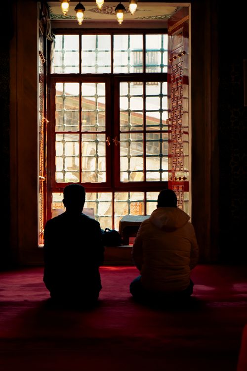 Free Two people sit in quiet contemplation, silhouetted against a sunlit window. Indoor setting. Stock Photo