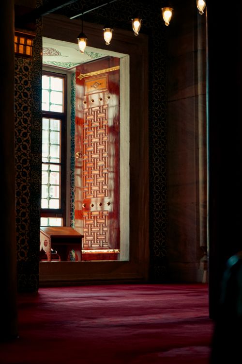 Free Sunlit interior of a historic mosque with ornate patterns and warm lighting. Stock Photo