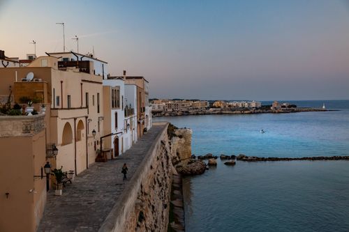 Free A scenic coastal town with historic architecture and calm sea view at sunset. Stock Photo