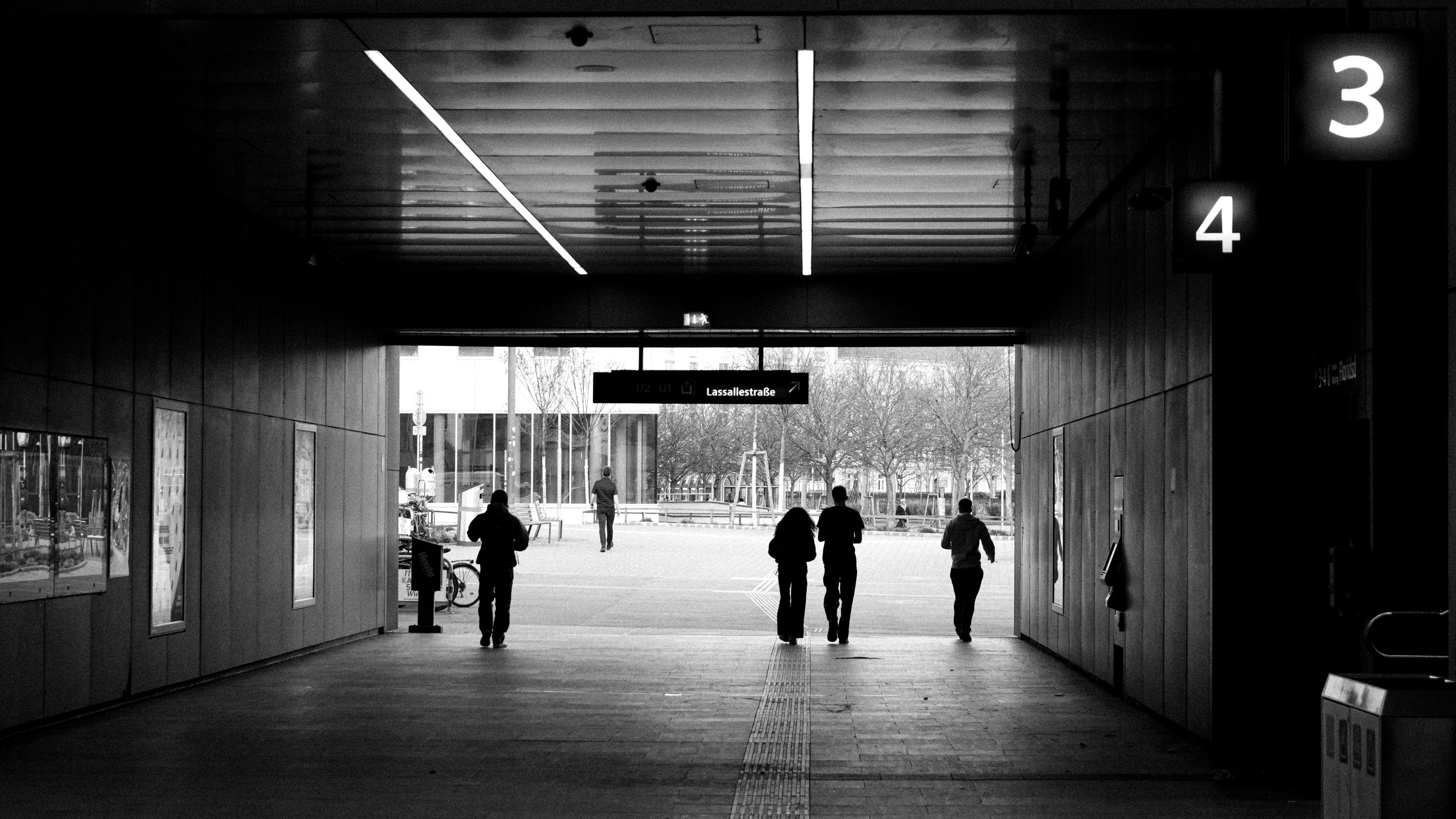 Silhouetted figures walking through a tunnel at Lassallestraße, Vienna with urban architecture background.