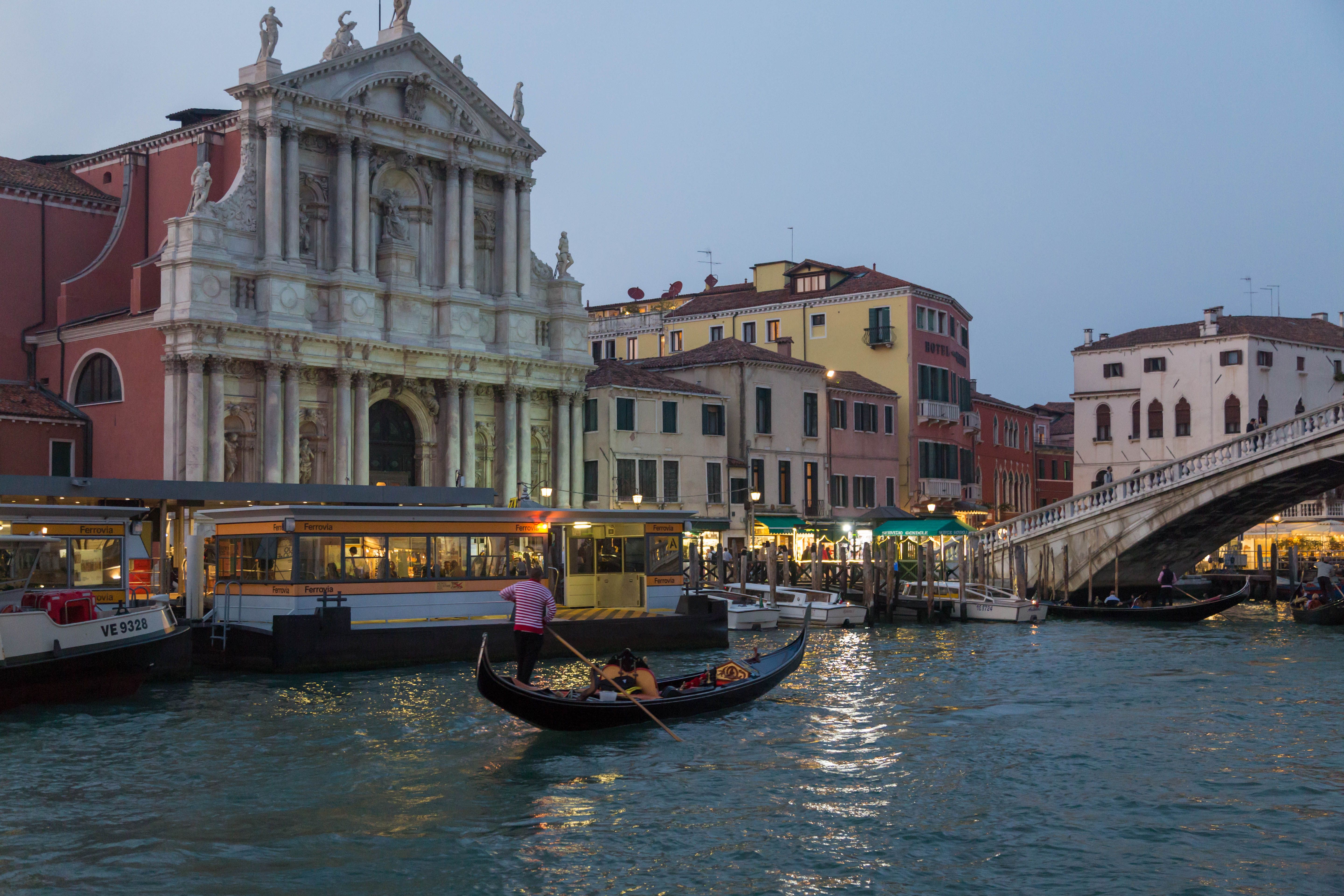 A scenic view of a gondola on a Venice canal near a historic building at dusk.