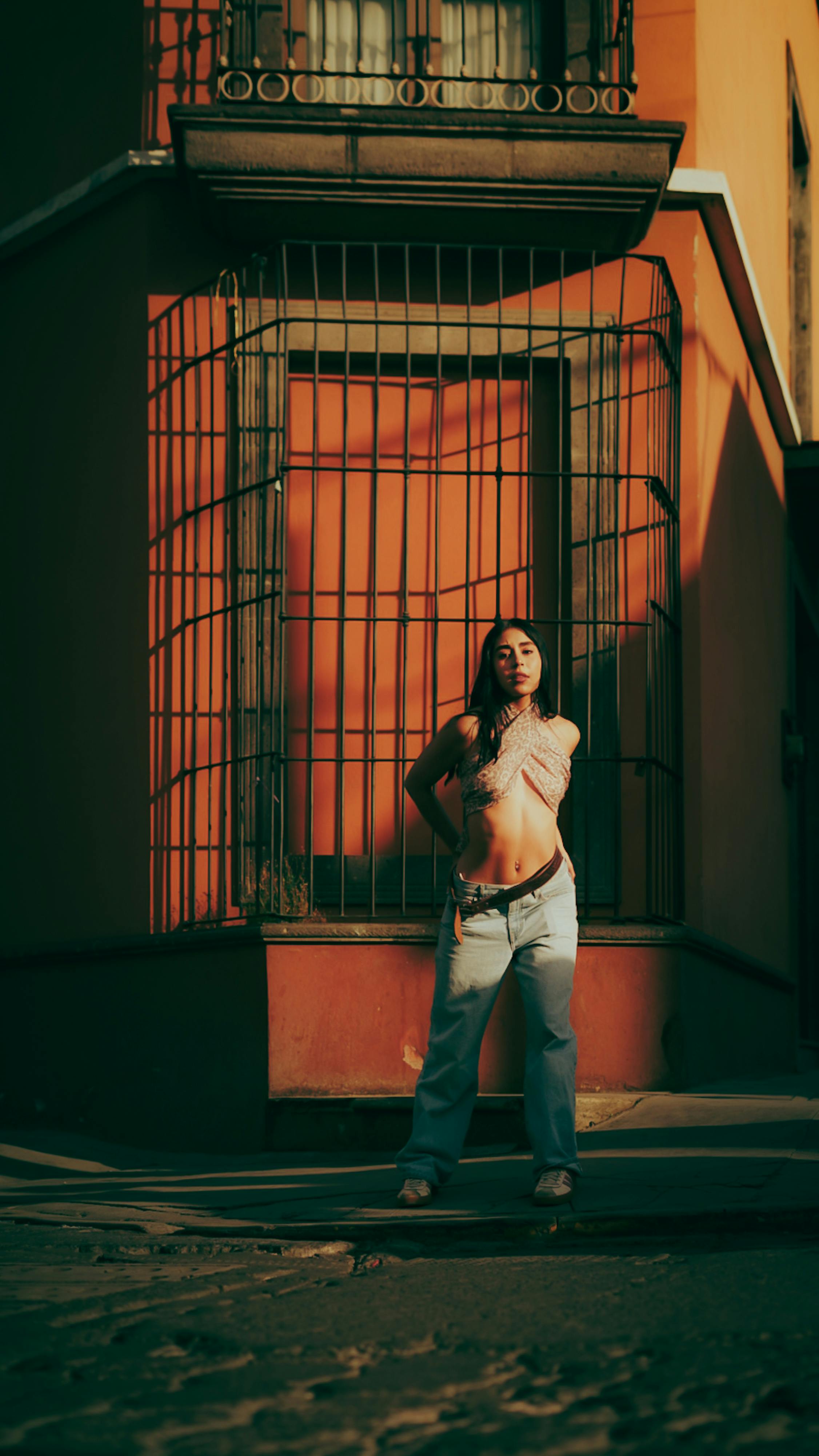 ฟรี หญิงสาวทันสมัยโพสท่าถ่ายรูปหน้ากำแพงเมืองสีสันสดใส เผยให้เห็นสไตล์สตรีทสุดเก๋ คลังภาพถ่าย