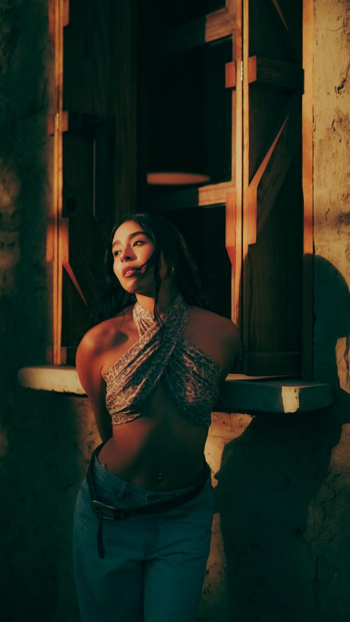 Free A woman basks in warm, glowing sunlight by a rustic window, creating a peaceful and artistic ambiance. Stock Photo