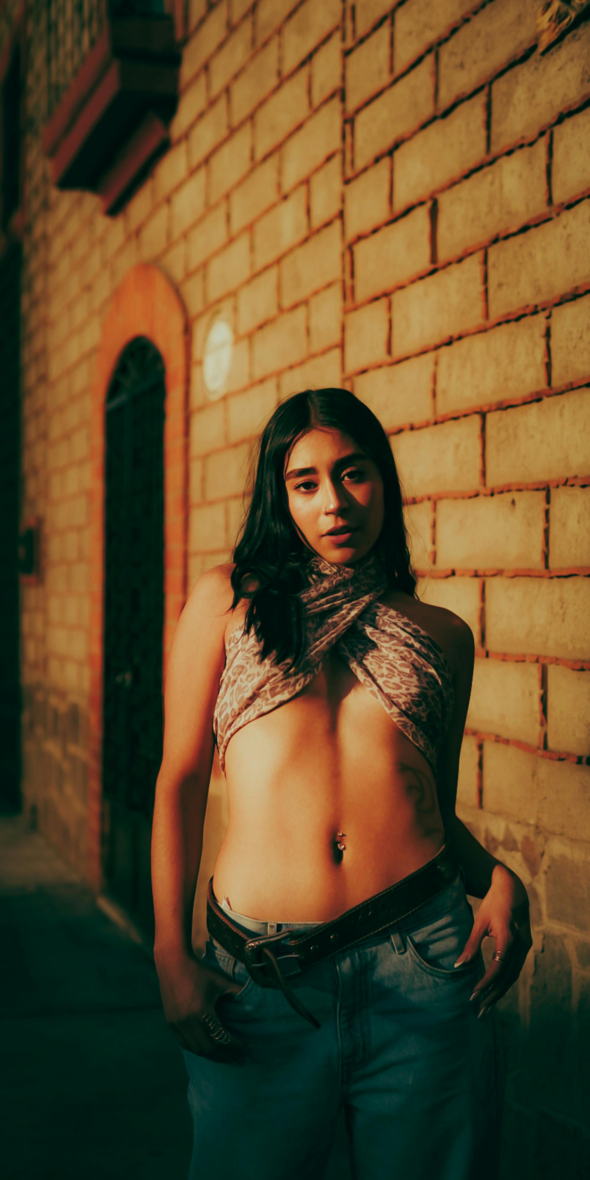 bezplatná Sebevědomá mladá žena pózuje v ulicích města při západu slunce a předvádí městskou módu. Základová fotografie