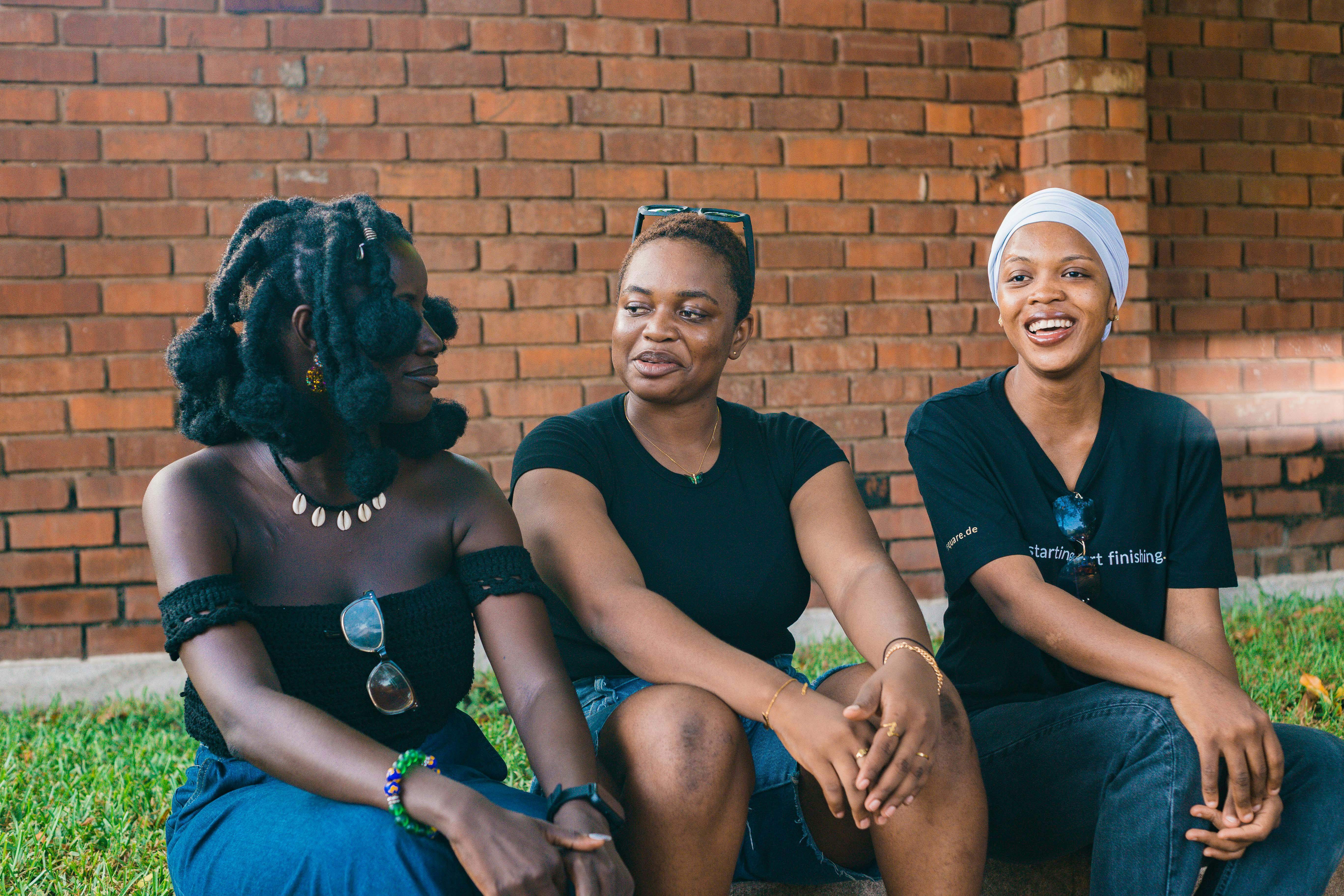 免費 在加納首都阿克拉，三名女子在戶外靠著磚牆輕鬆交談。 圖庫相片