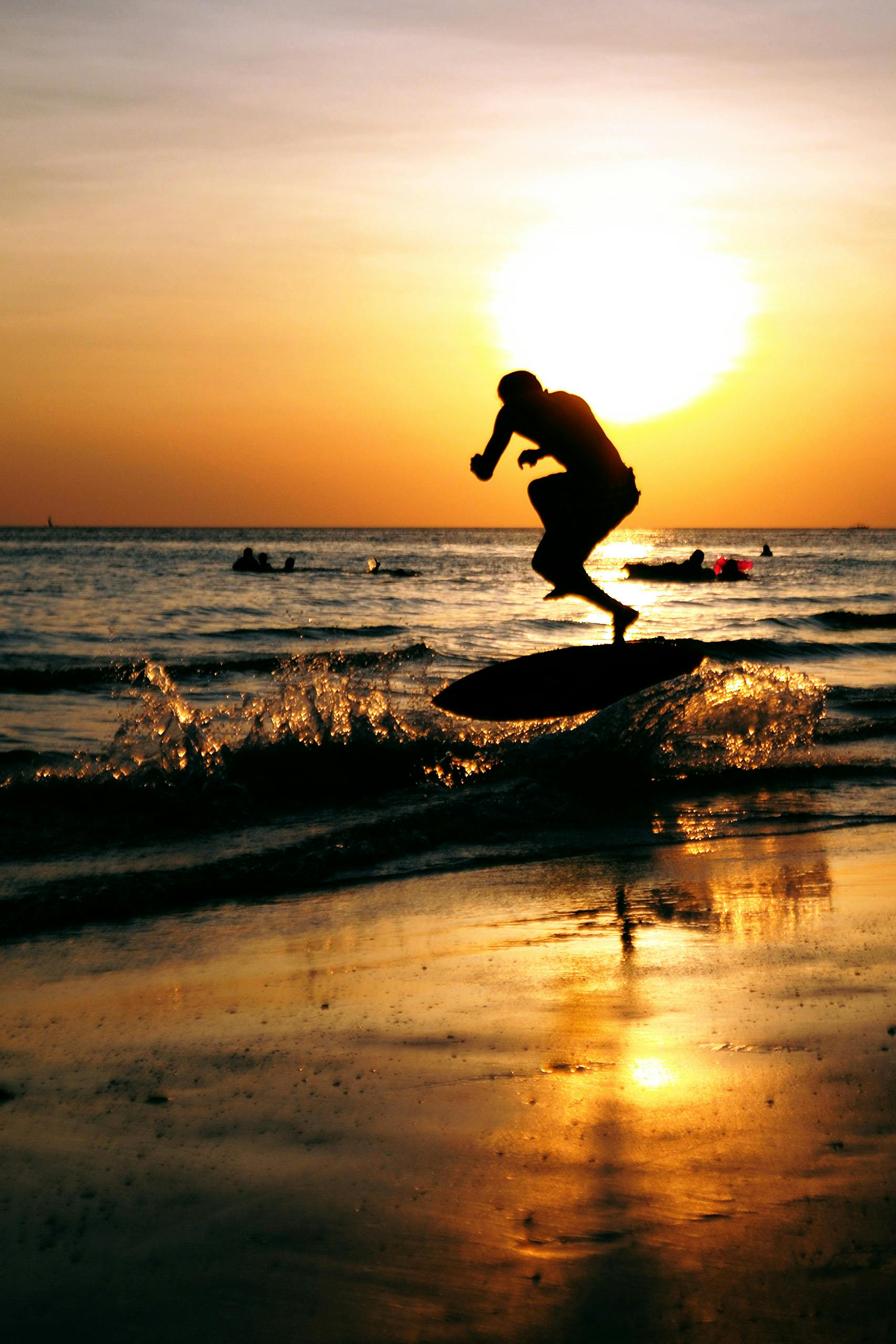 免費 日落時分，有人在海浪上玩滑板，勾勒出動感的剪影。 圖庫相片