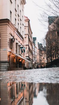 Cozy autumn street scene in Stockholm, reflecting buildings and lights on wet cobblestones.