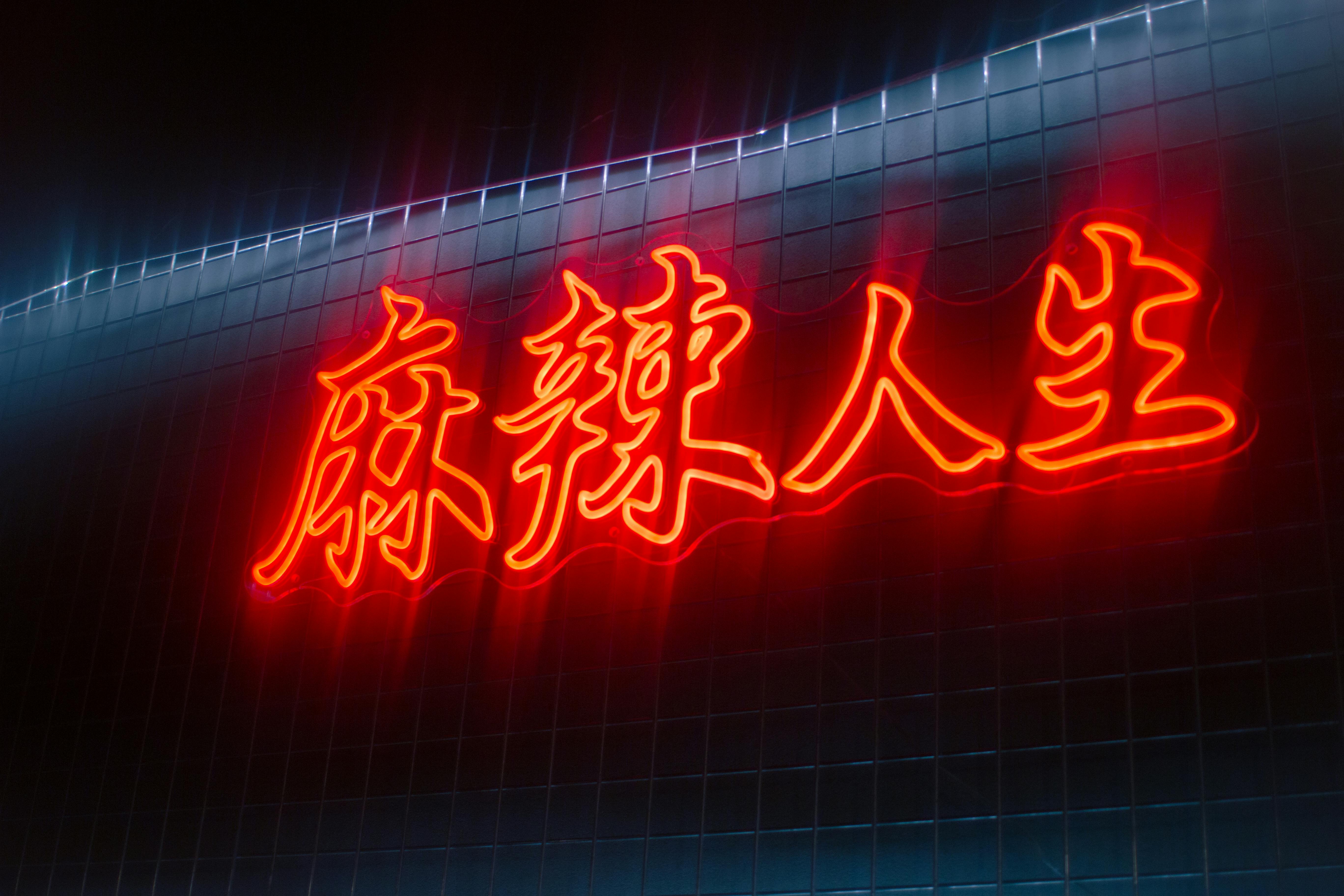 ingyenes Piros neonreklám kínai karakterekkel egy csempefal előtt, éjszakai felvételen. Stockfotó