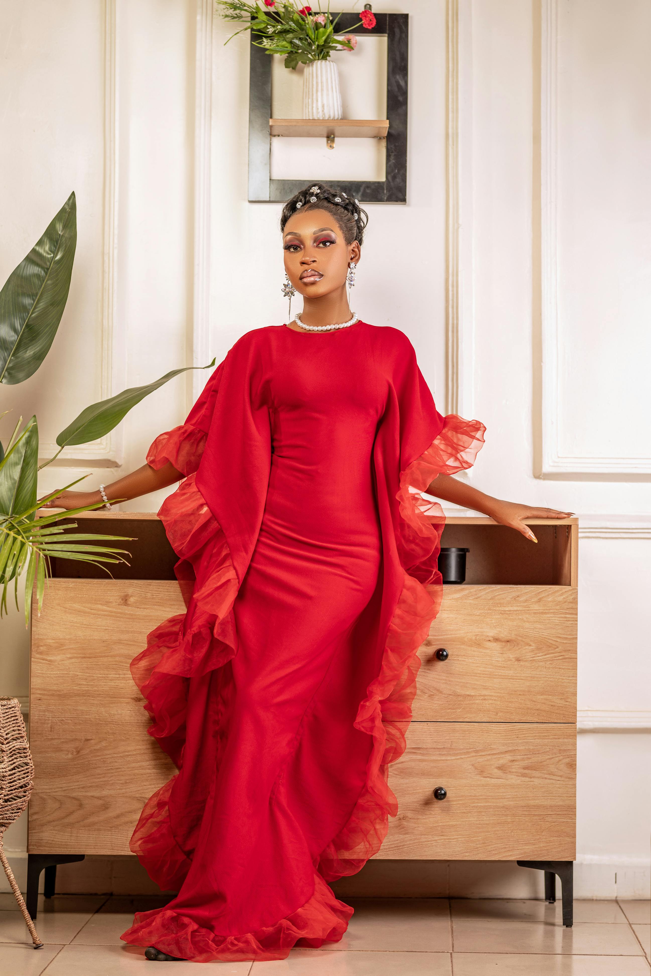 免費 一位時尚女性身穿優雅的紅色洋裝在室內擺姿勢，展現時尚與優雅。 圖庫相片