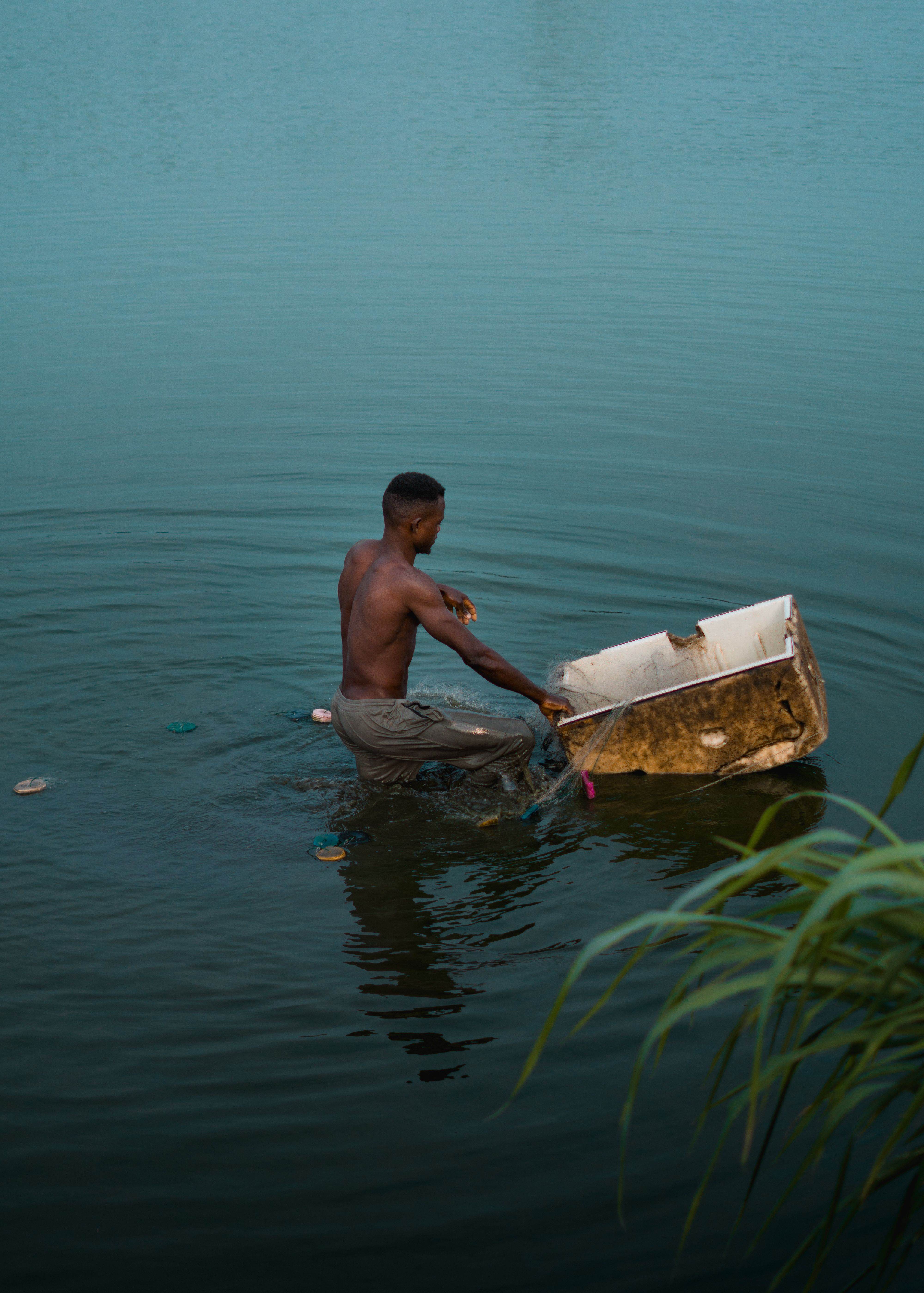Man Fishing with Makeshift Net in Tranquil Lake · Free Stock Photo