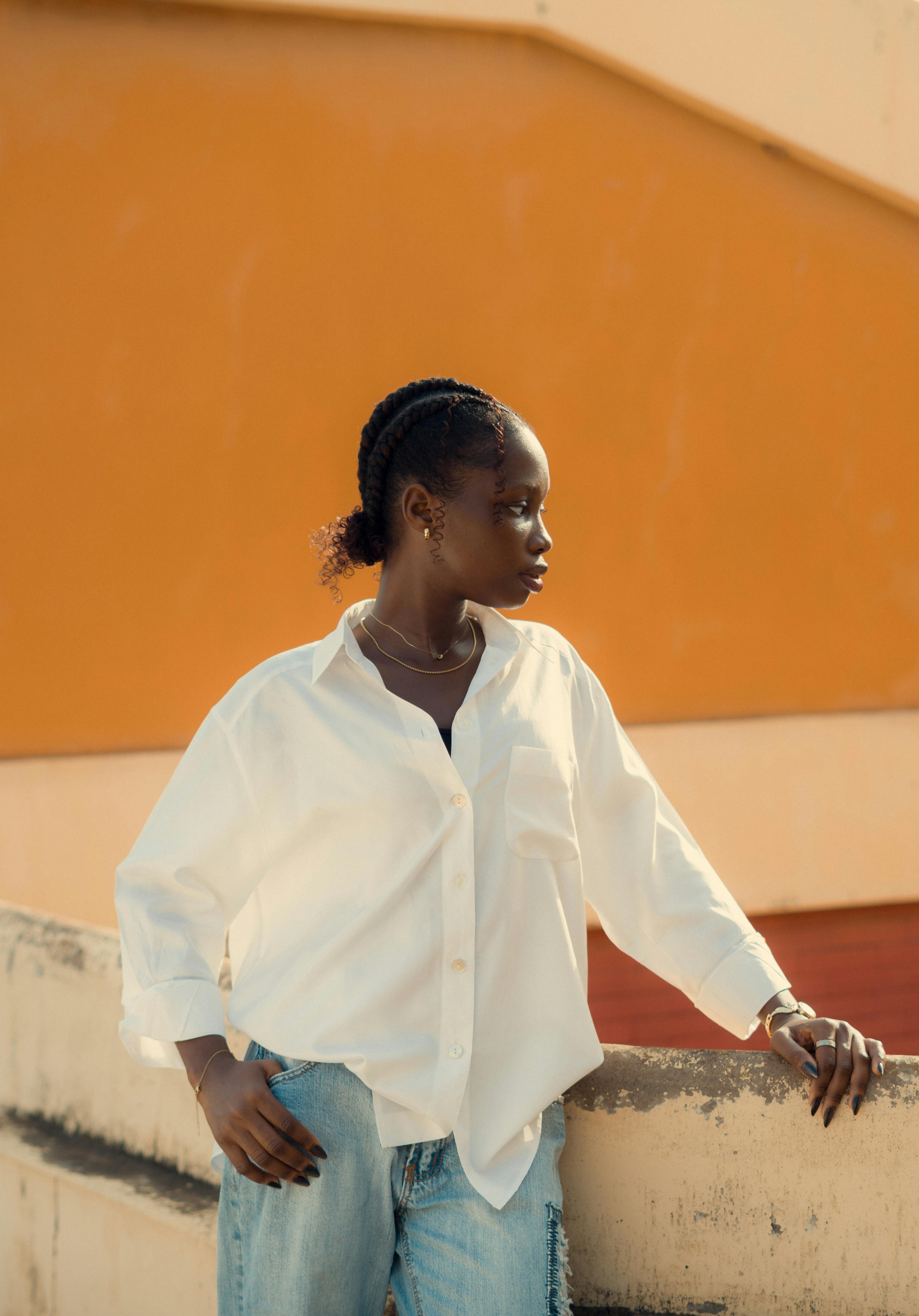 Kostenlos Eine junge Frau in legerer Kleidung steht selbstbewusst vor einer farbenfrohen Wand im Freien. Stock-Foto