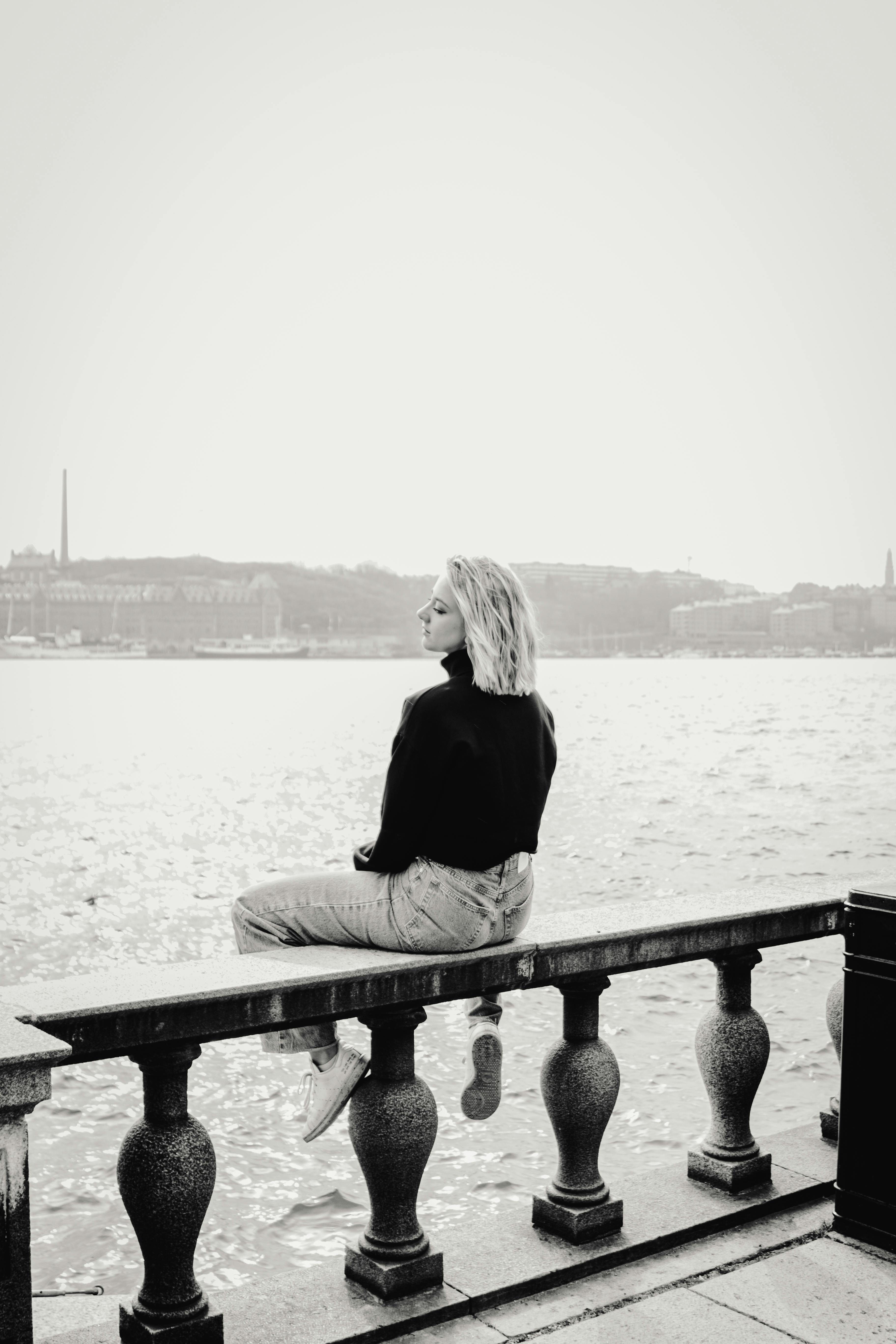 Безкоштовне Жінка сидить на набережній у Стокгольмі, Швеція, дивлячись на воду. стокове фото