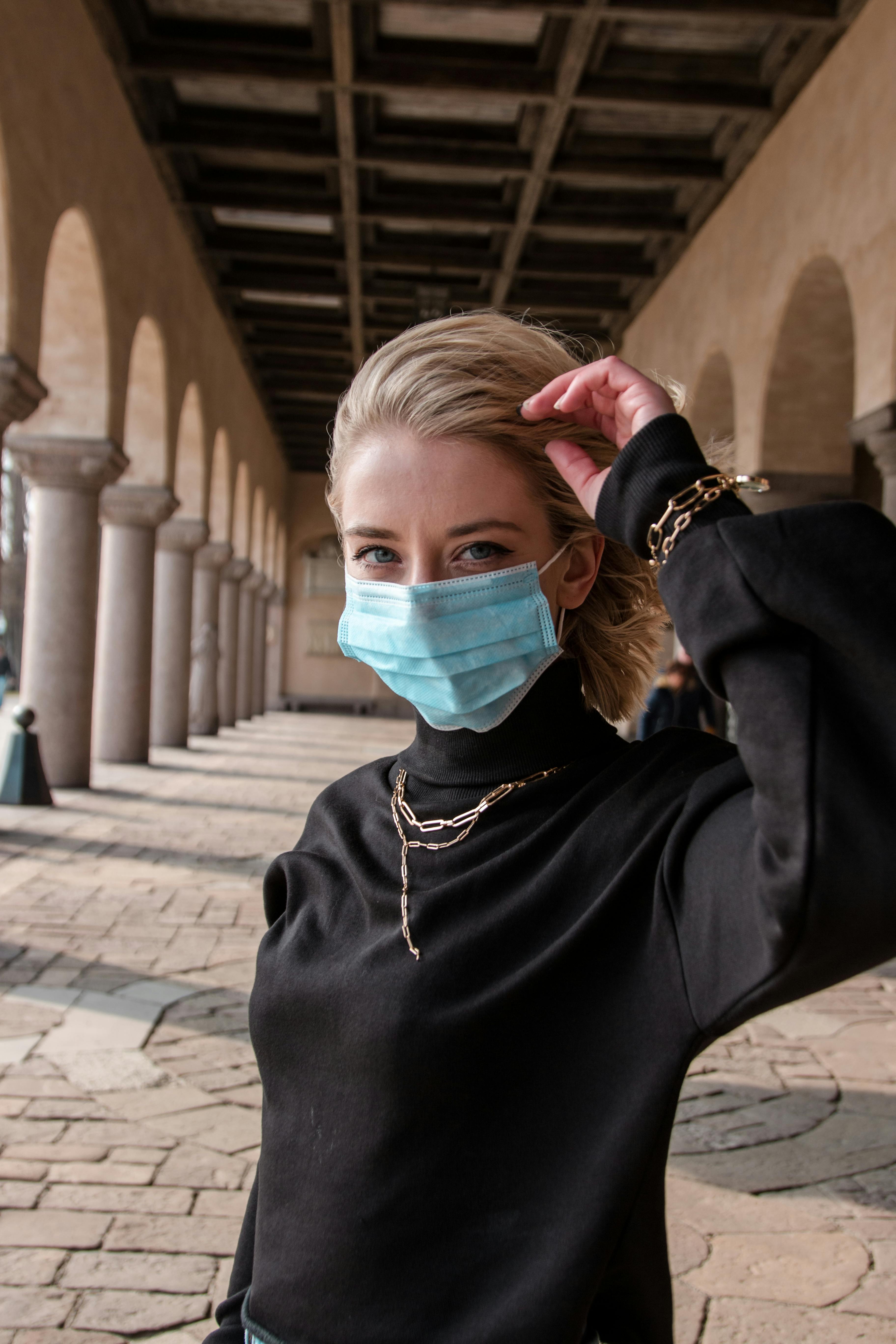 免費 一位戴著口罩的年輕女子站在斯德哥爾摩市政廳的拱門下。 圖庫相片