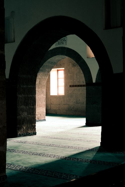 Free Ethereal view of arches illuminated by a warm window light in a serene indoor setting. Stock Photo
