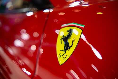 Free Detailed view of a classic sports car emblem on sleek red paint, showcasing luxury and style. Stock Photo