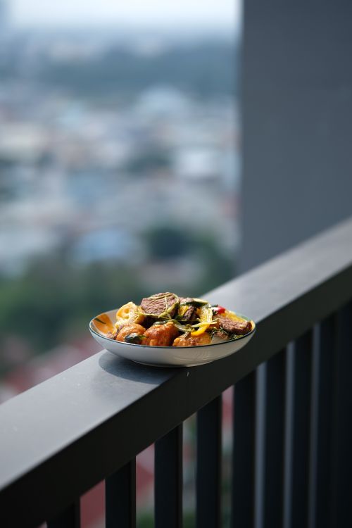Free A tantalizing dish of grilled vegetables placed outdoors on a balcony railing, perfect for alfresco dining. Stock Photo