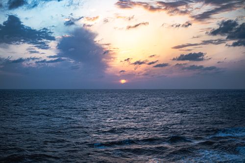 Free Peaceful ocean view at sunset with dramatic clouds and vibrant colors. Stock Photo