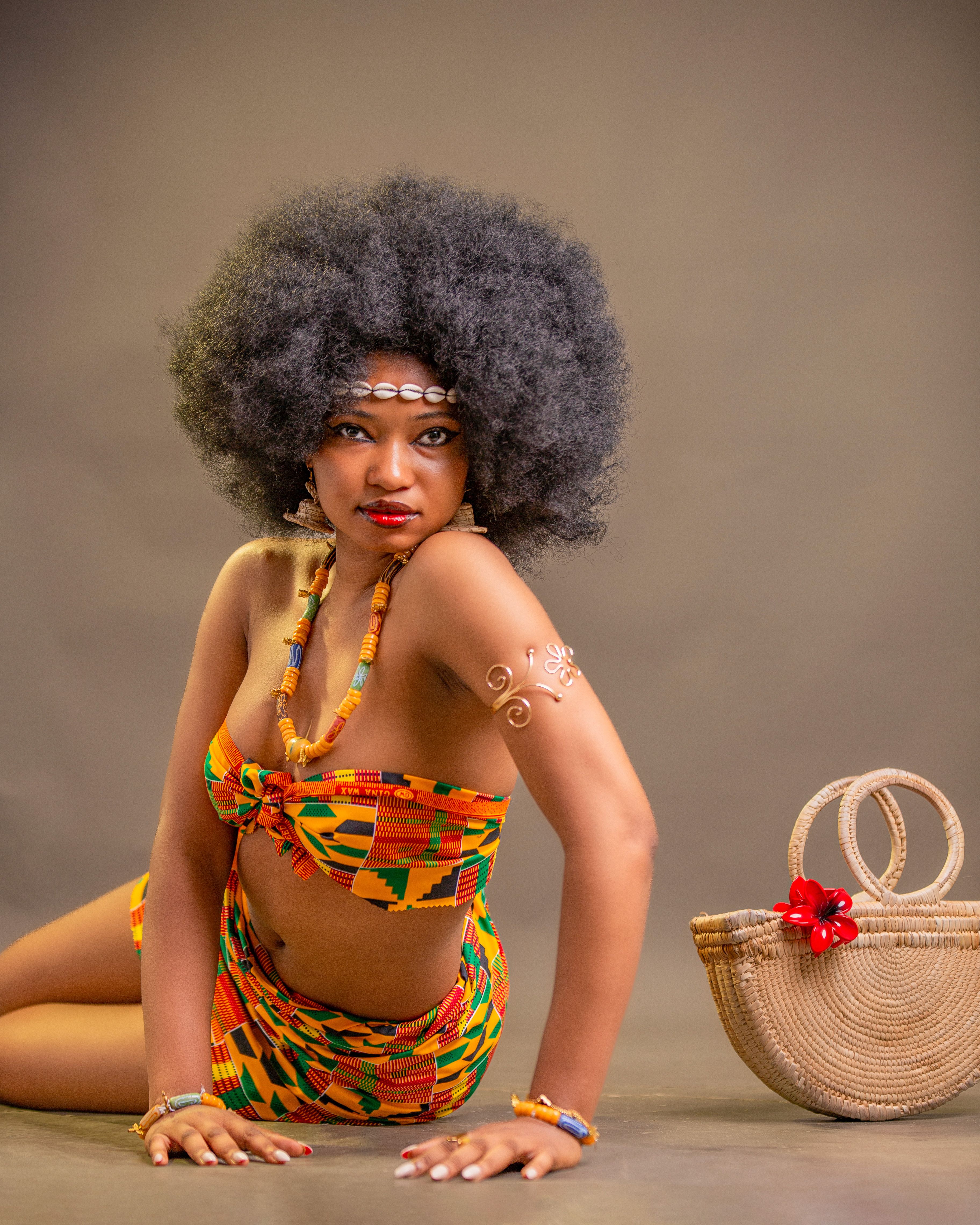 Portrait of a Ghanaian woman in vibrant Kente cloth with intricate afro hairstyle.